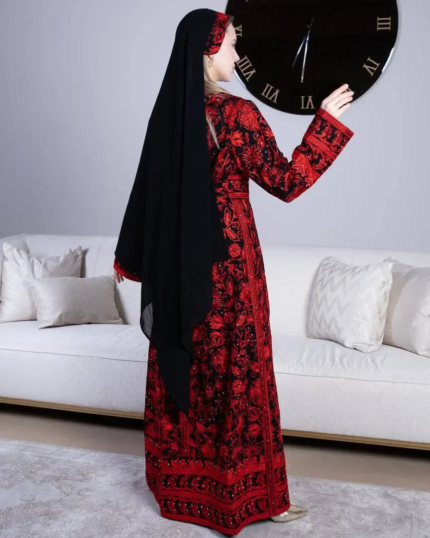Palestinian Elegance traditional embroidered kaftan in red and black worn with matching headscarf indoors