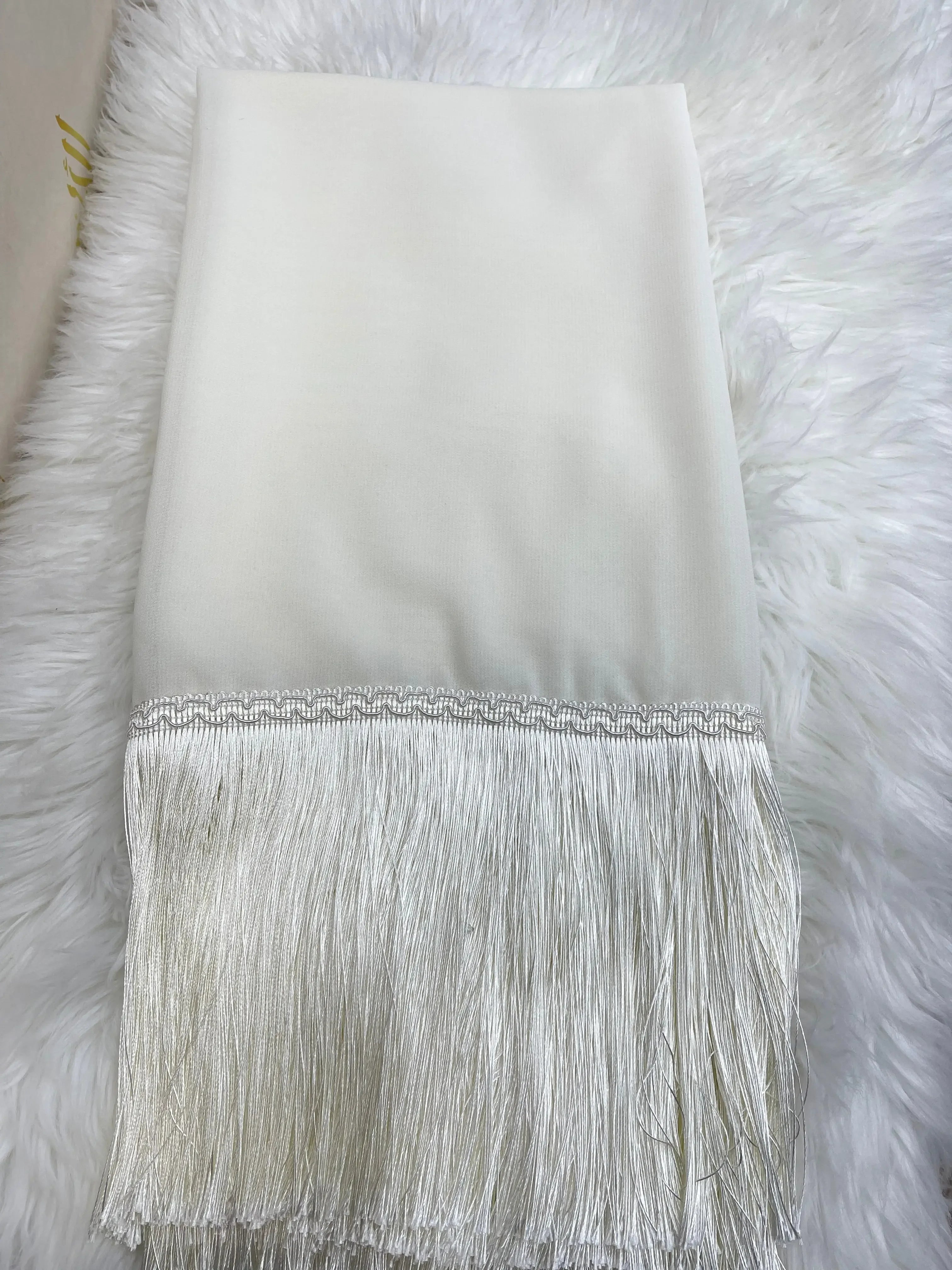 White traditional khirka shal hijab with fringe detail from Palestinian Elegance on fluffy white background