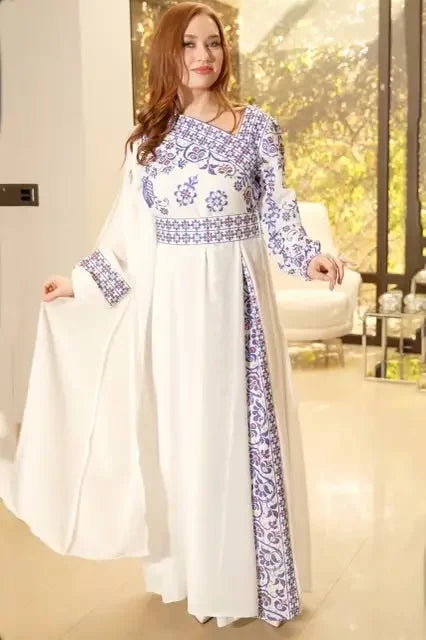 White traditional Palestinian embroidery dress with blue floral patterns worn by woman in elegant setting