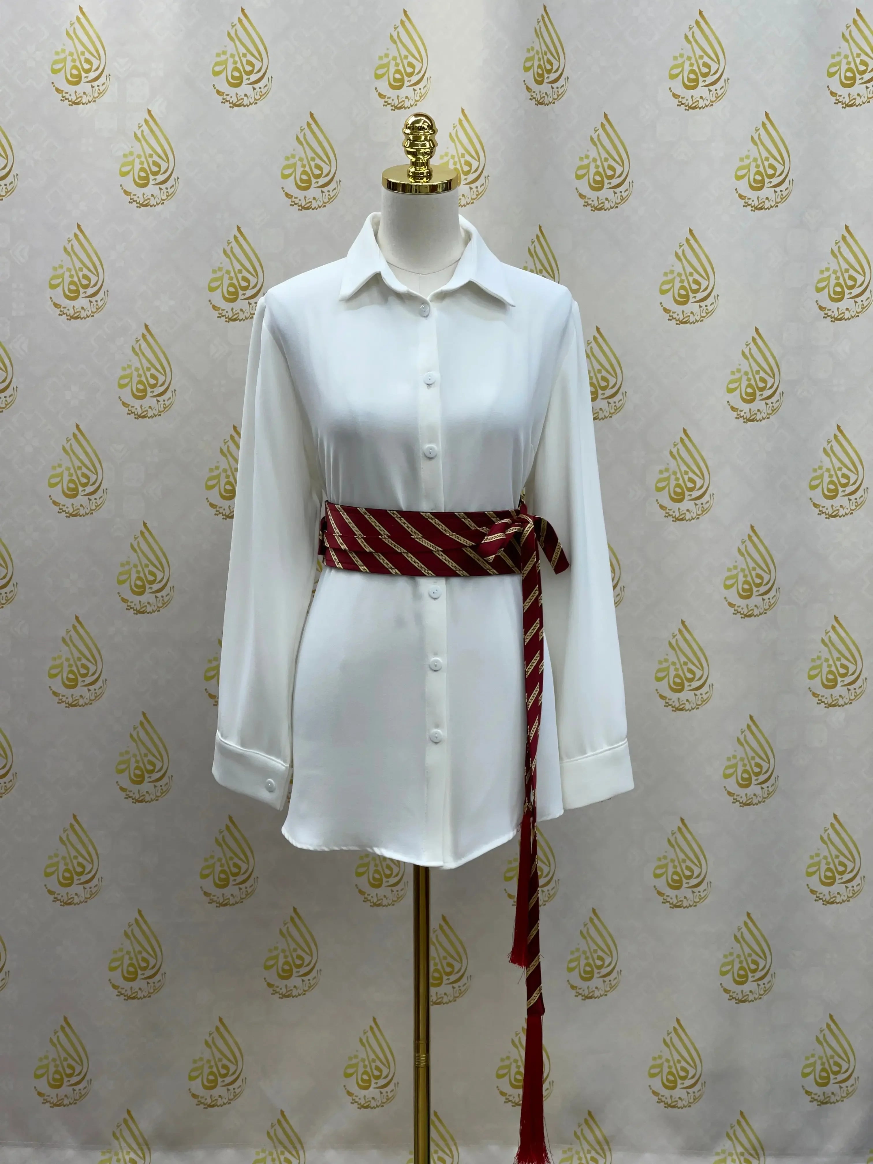 Embroidered kashmir belt in red and white wrapped around a white button-up shirt on a mannequin