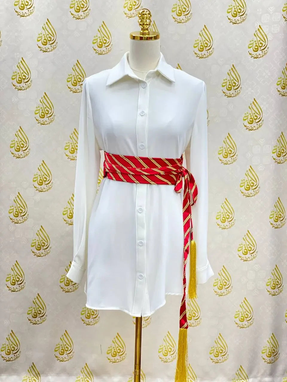 Palestinian Elegance embroidered kashmir belt in red and gold worn over a white button-down dress