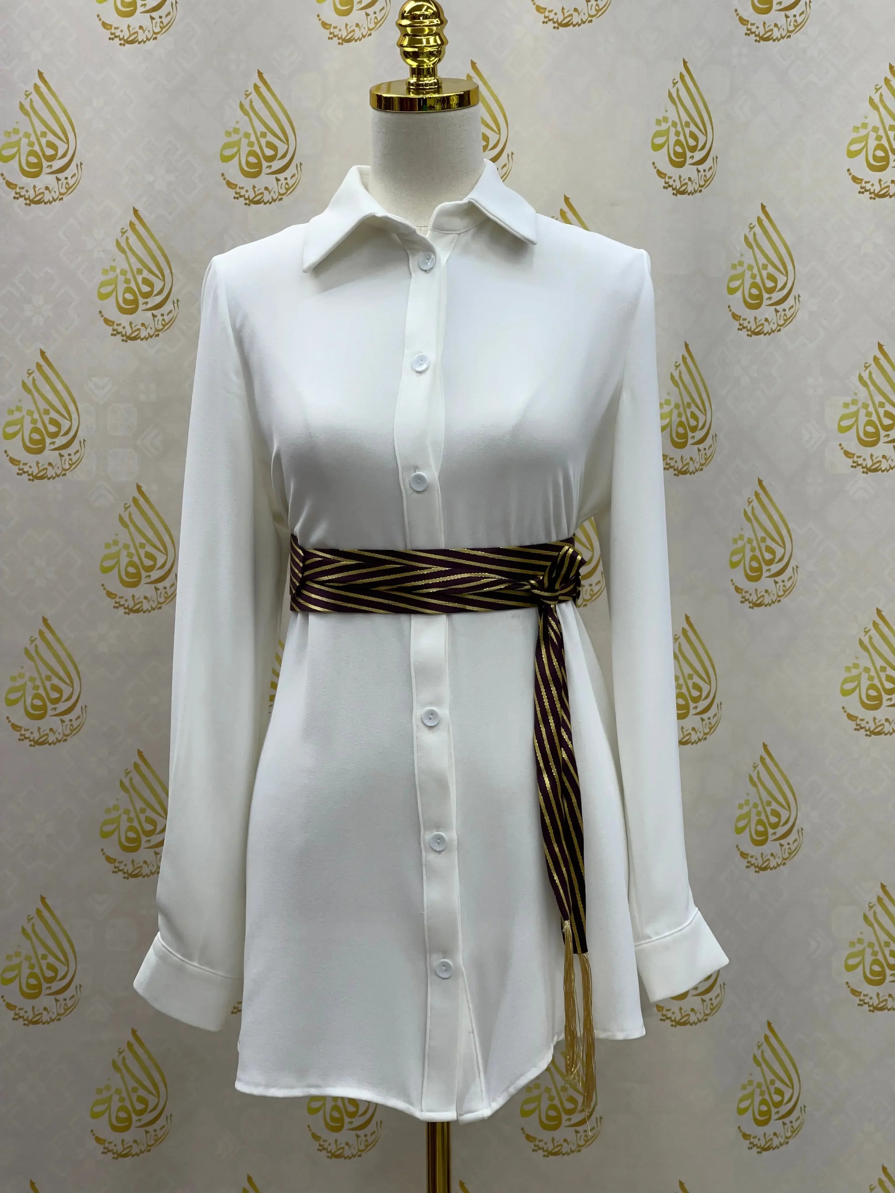 White button-up shirt dress styled with a Palestinian Elegance embroidered saya belt tied at the waist