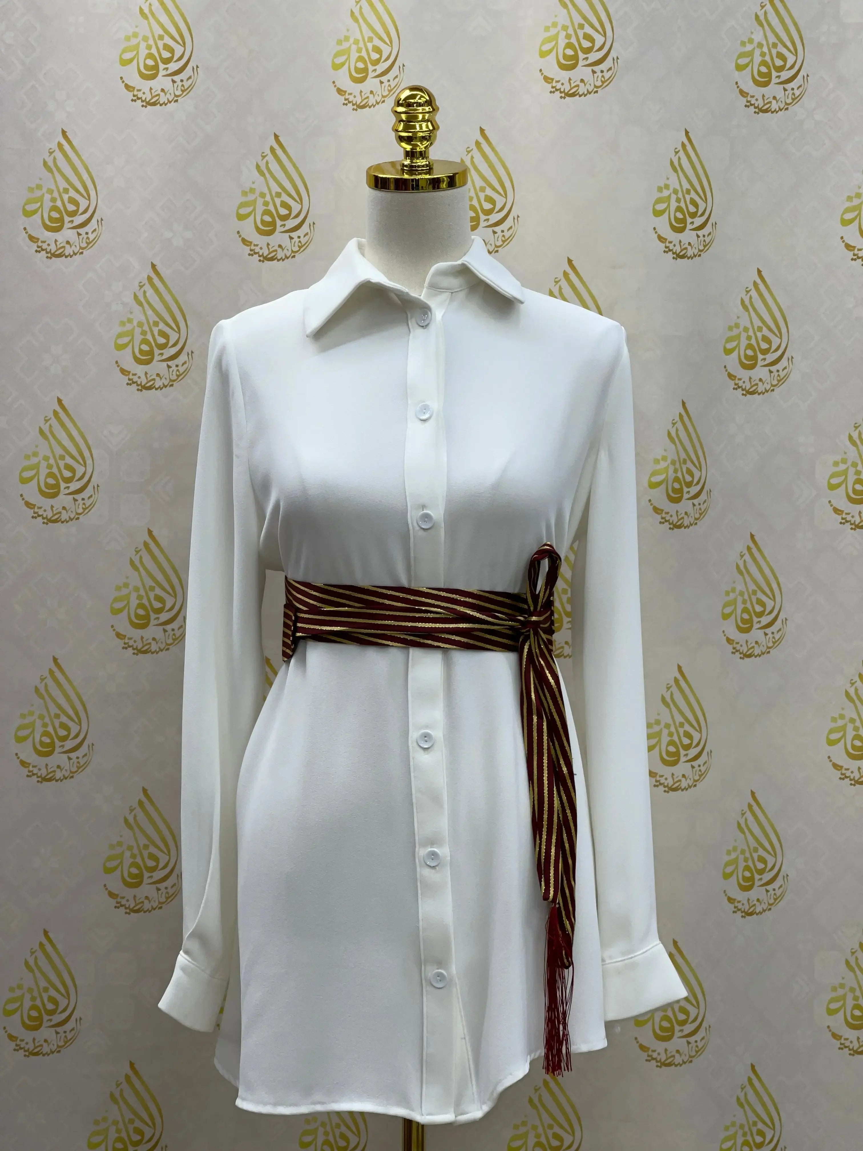 White long sleeve shirt dress with striped embroidered saya belt tied at the waist by Palestinian Elegance