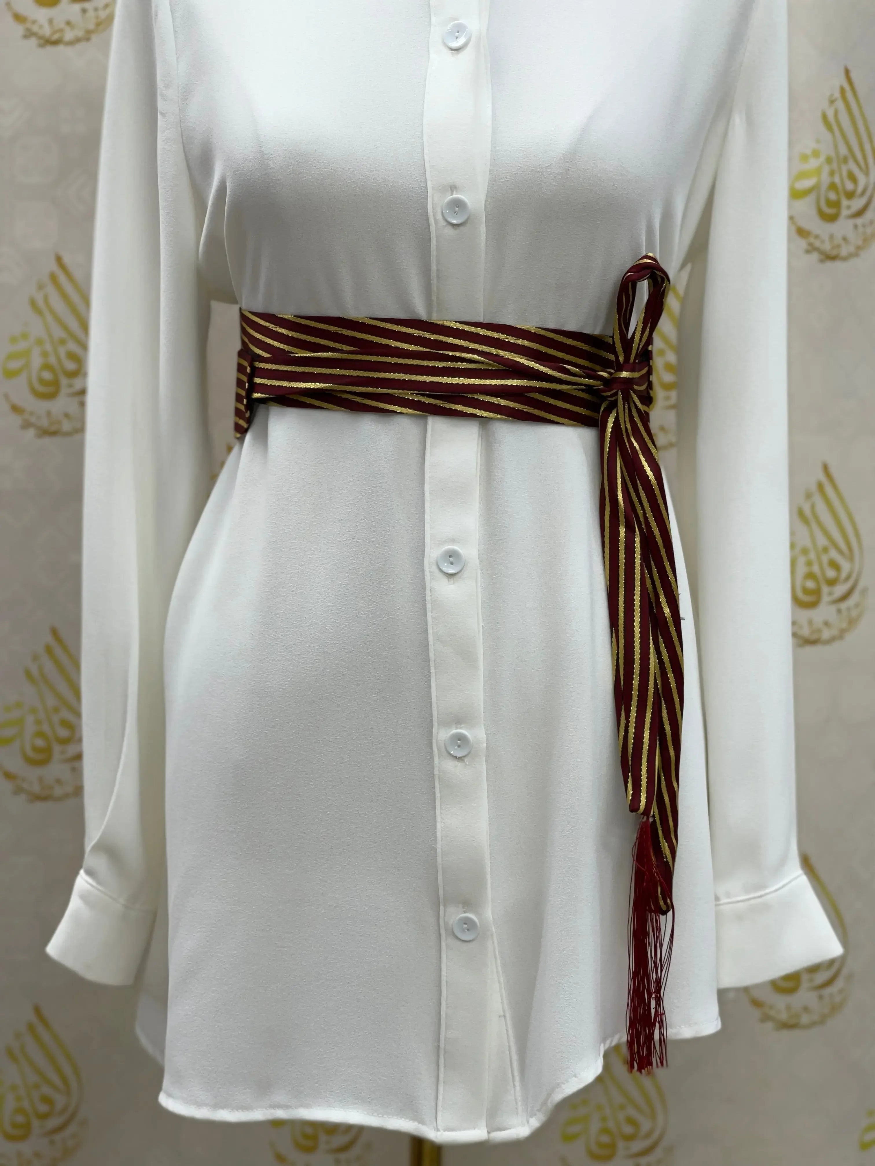 Palestinian Elegance embroidered saya belt in maroon and gold stripes tied around white dress