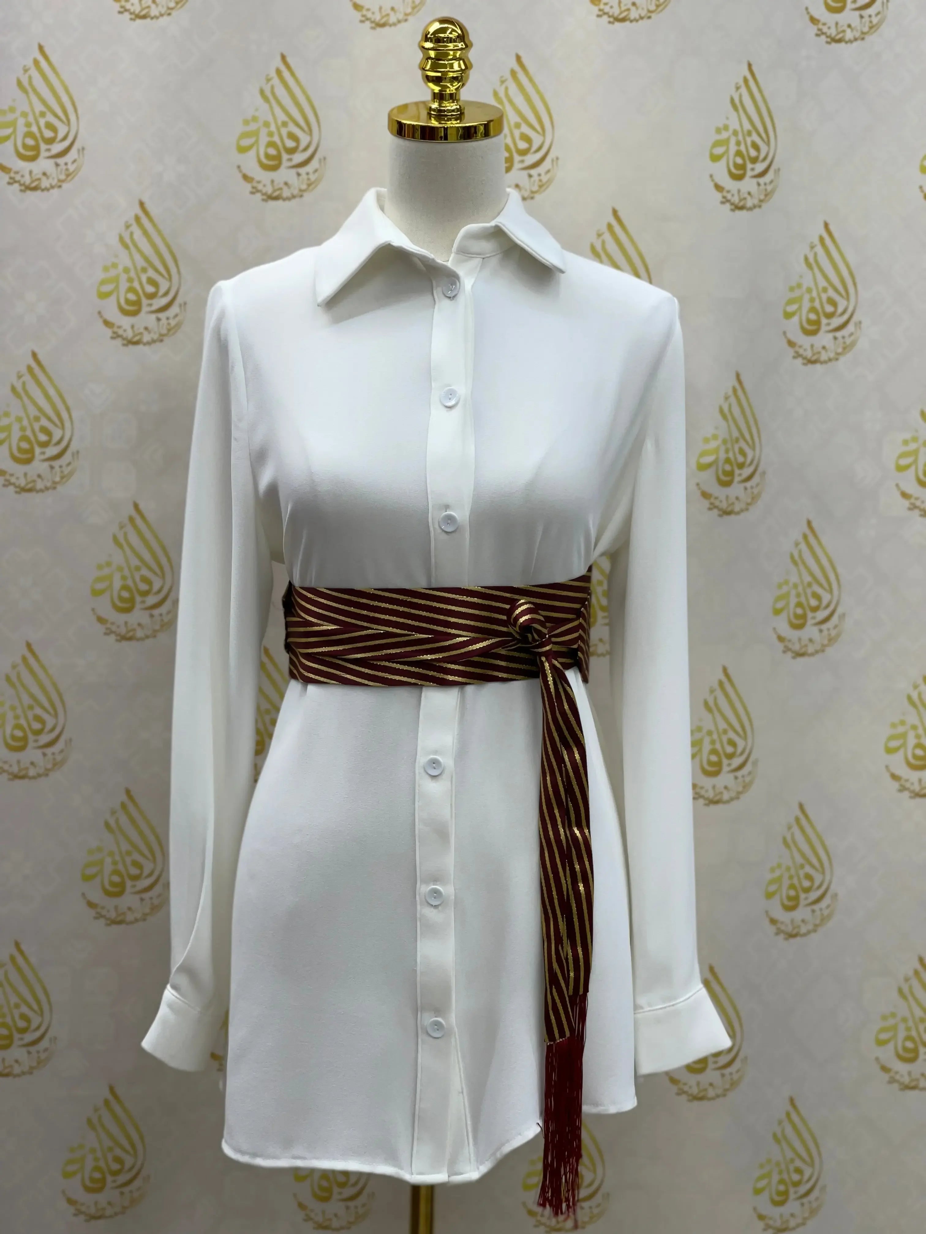 Embroidered waist belt for women in brown with gold stripes styled on white button-up shirt dress