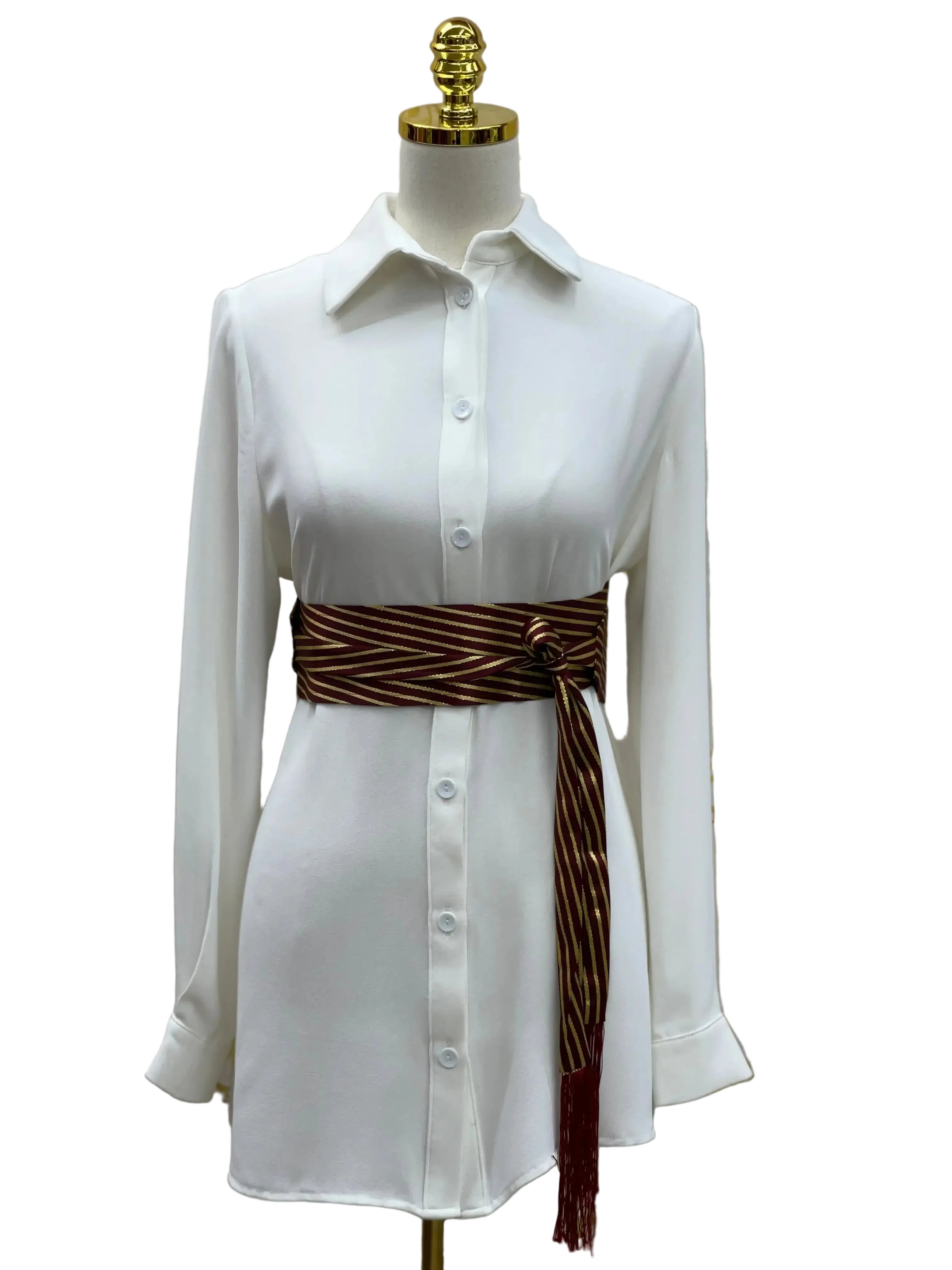 Embroidered waist belt for women in brown with gold stripes styled on white button-up shirt dress