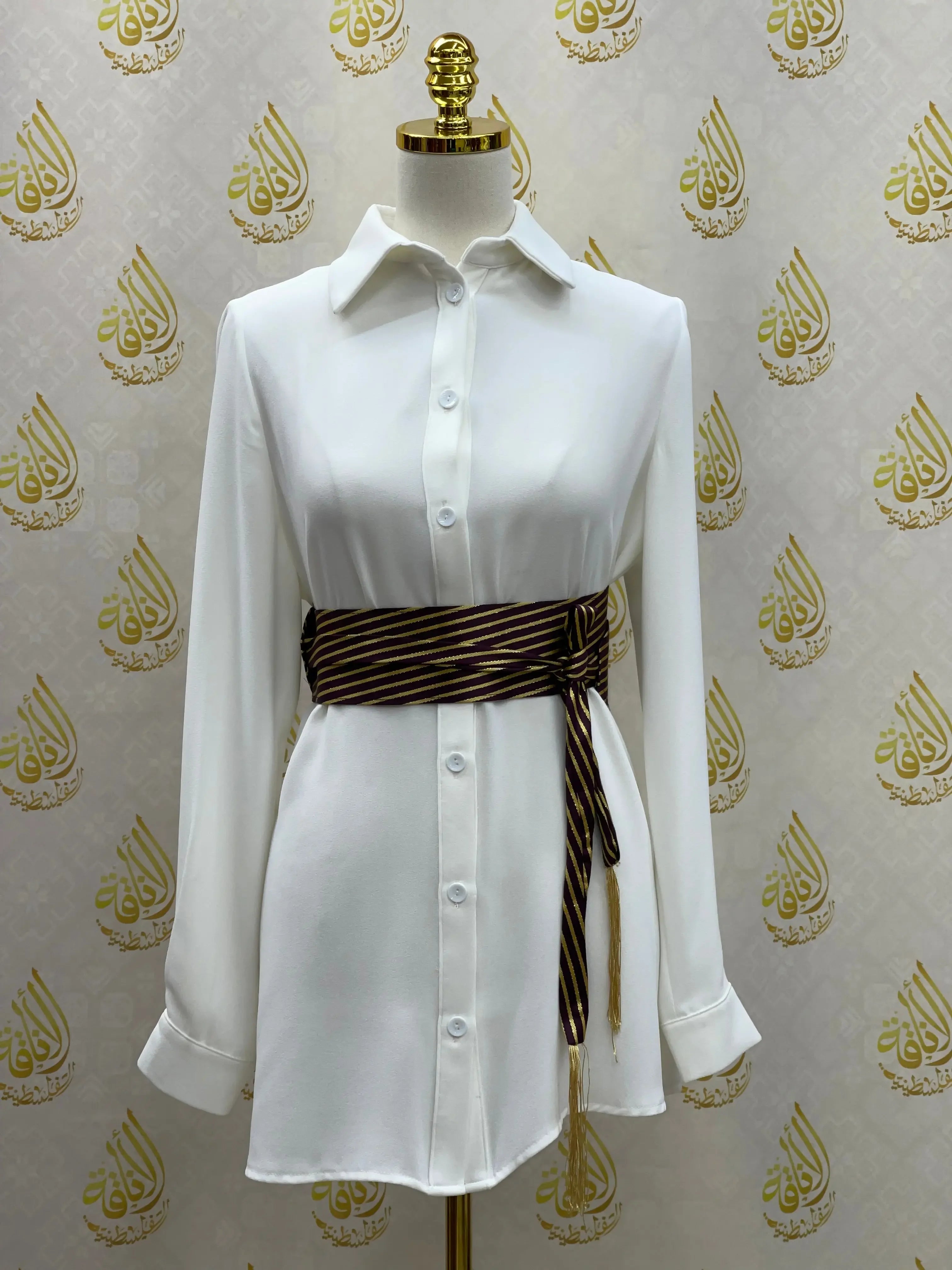 Embroidered waist belt for women in black and gold worn over a white button-down dress