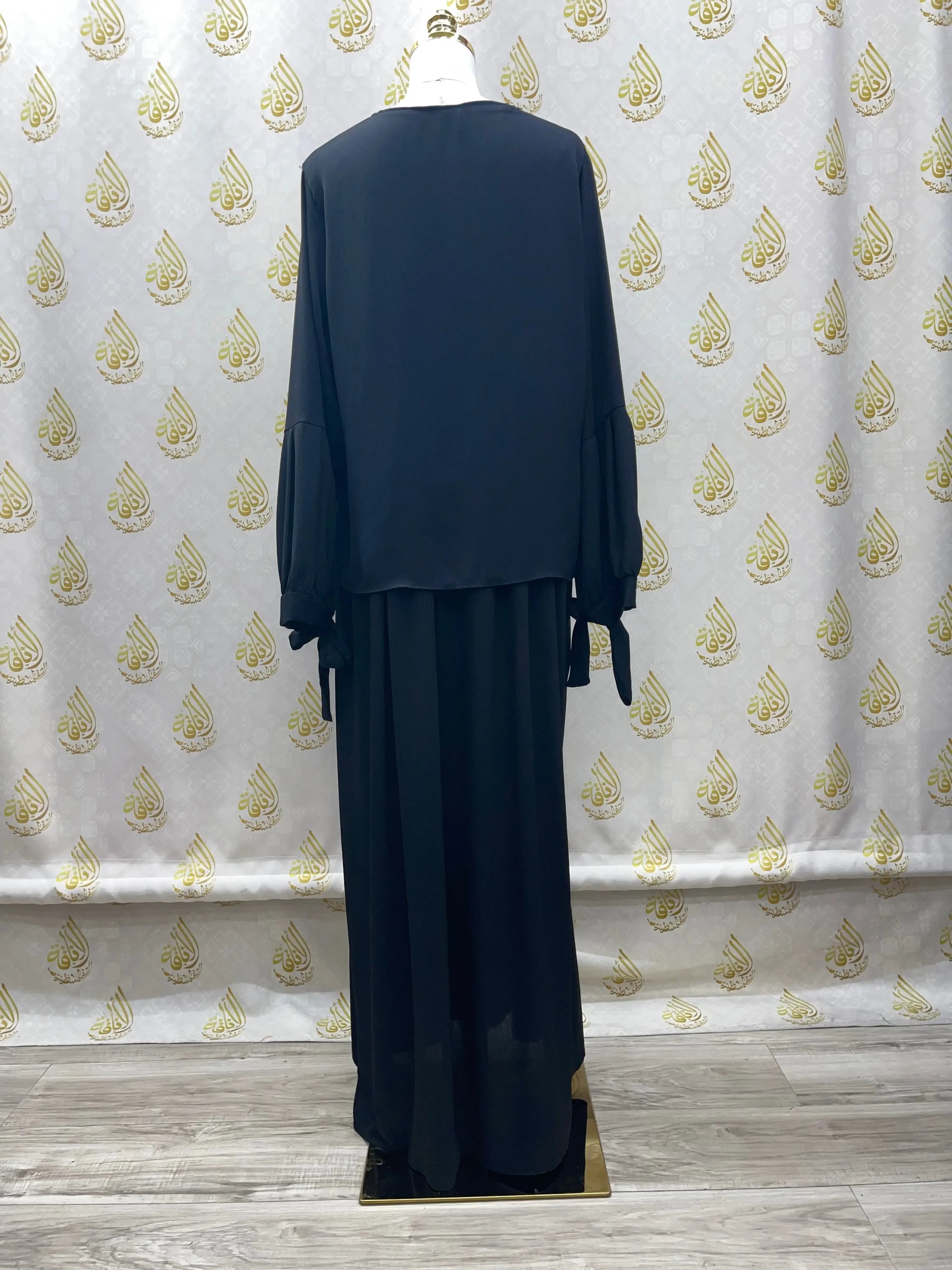 Plain black abaya from Palestinian Elegance displayed on a mannequin with long sleeves and a loose fit