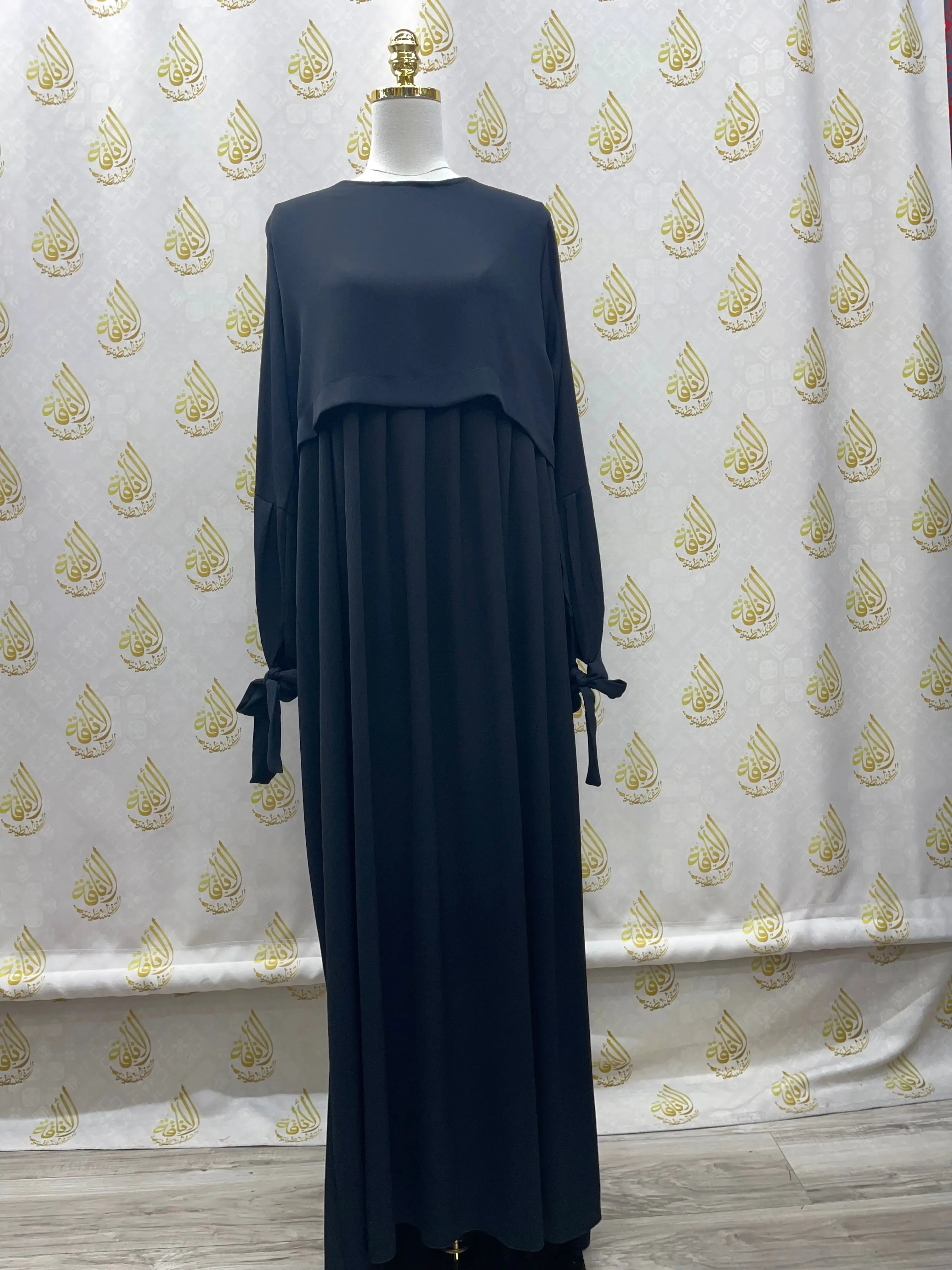 Palestinian Elegance plain black abaya with long sleeves and bow details on a mannequin