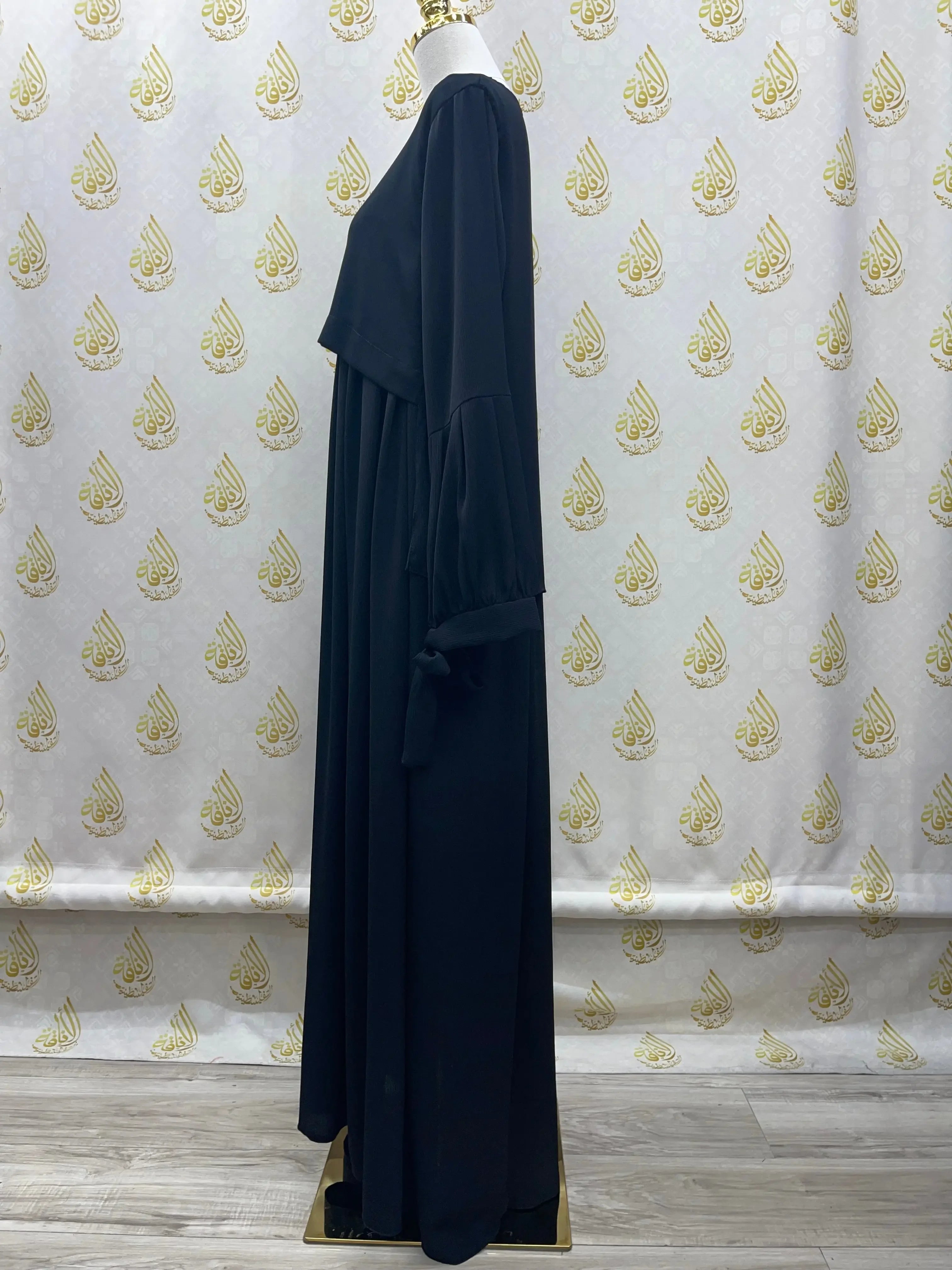 Plain black abaya from Palestinian Elegance displayed on mannequin showing long sleeves and flowing fabric