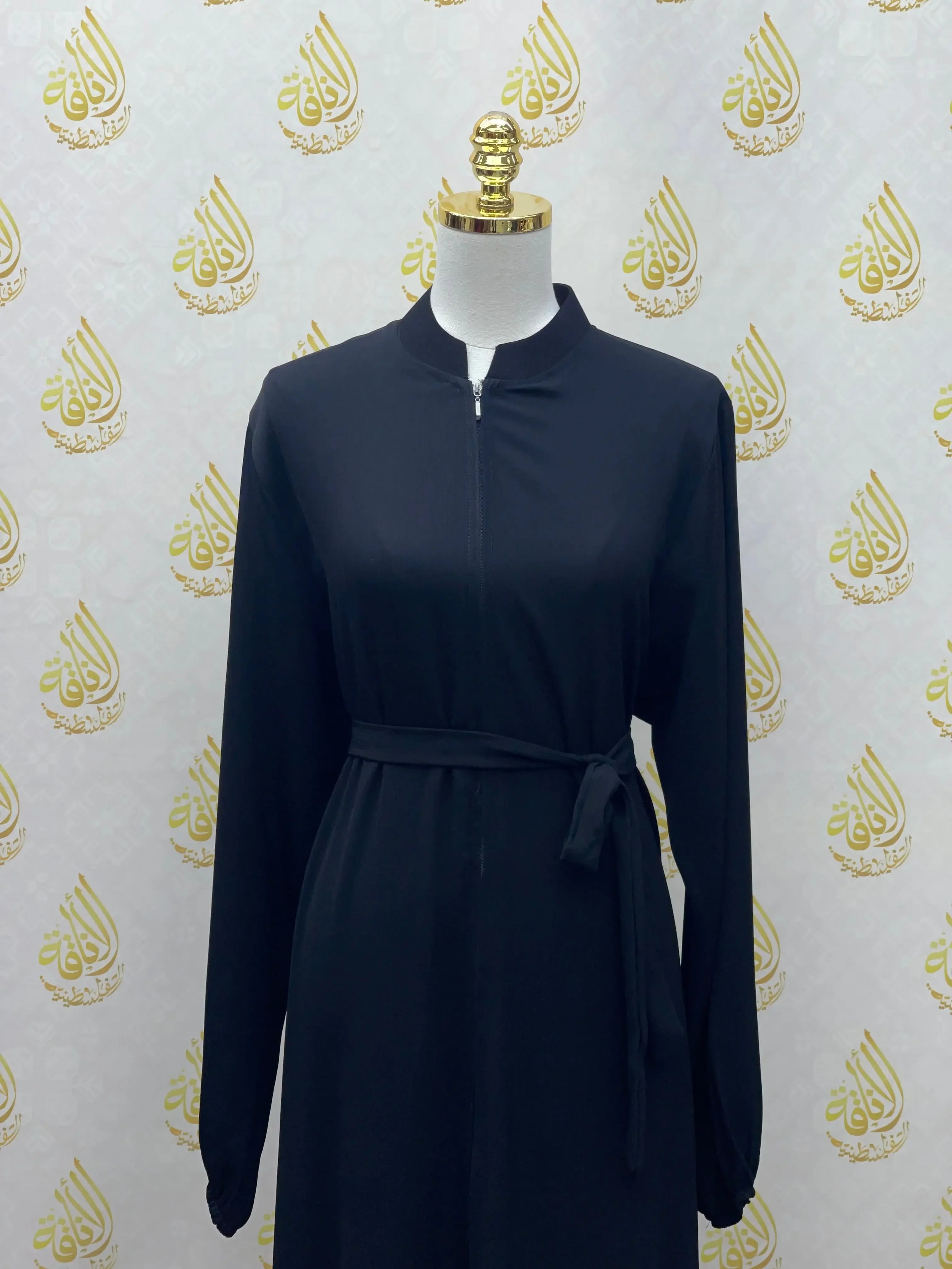 Plain black abaya with long sleeves and waist tie by Palestinian Elegance on mannequin