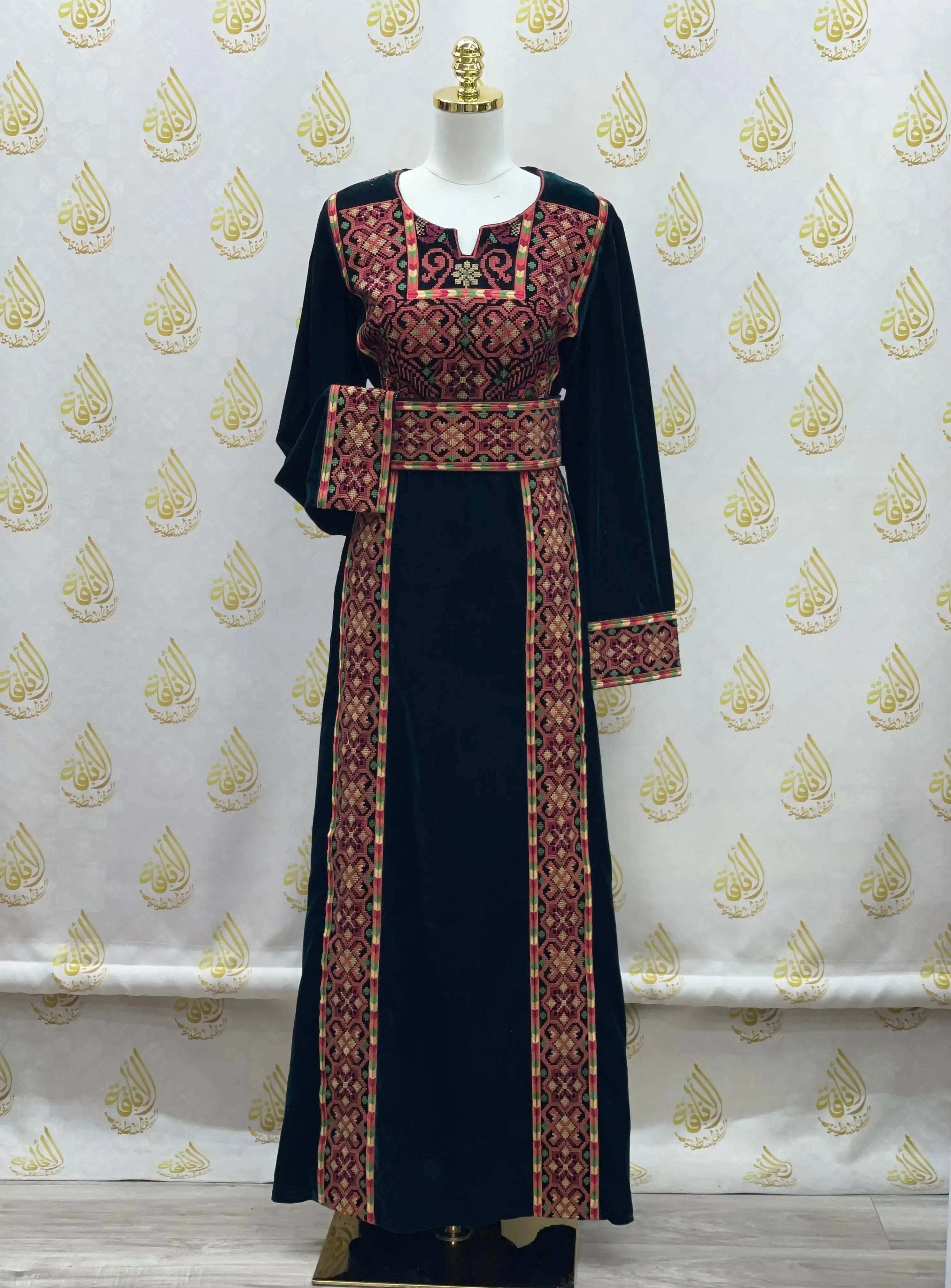 Palestinian Elegance velvet traditional thoub in dark blue with intricate red and gold embroidery on a mannequin