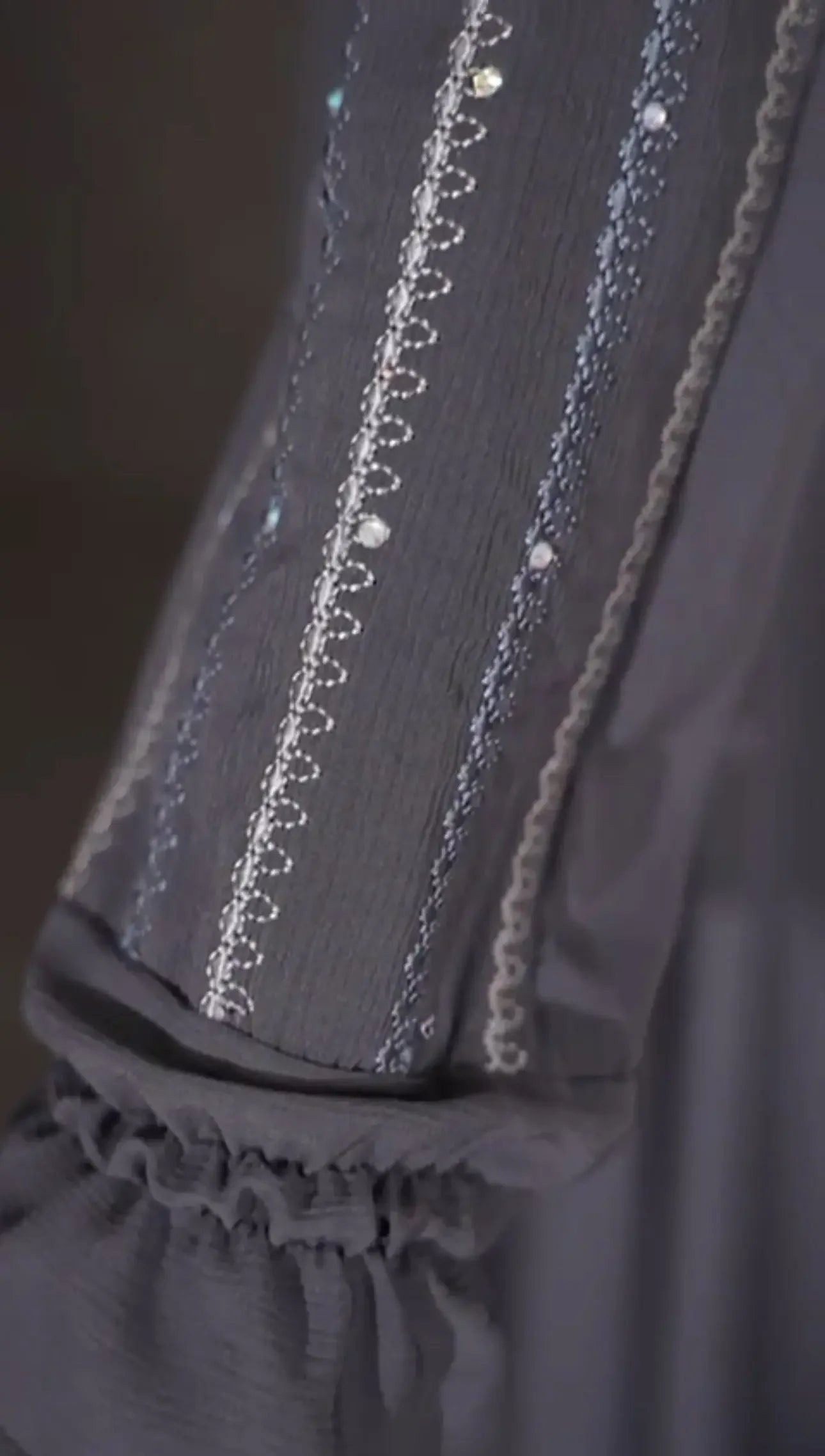 Close-up of intricate embroidery on sleeve of versatile abaya dress by Palestinian Elegance in dark fabric