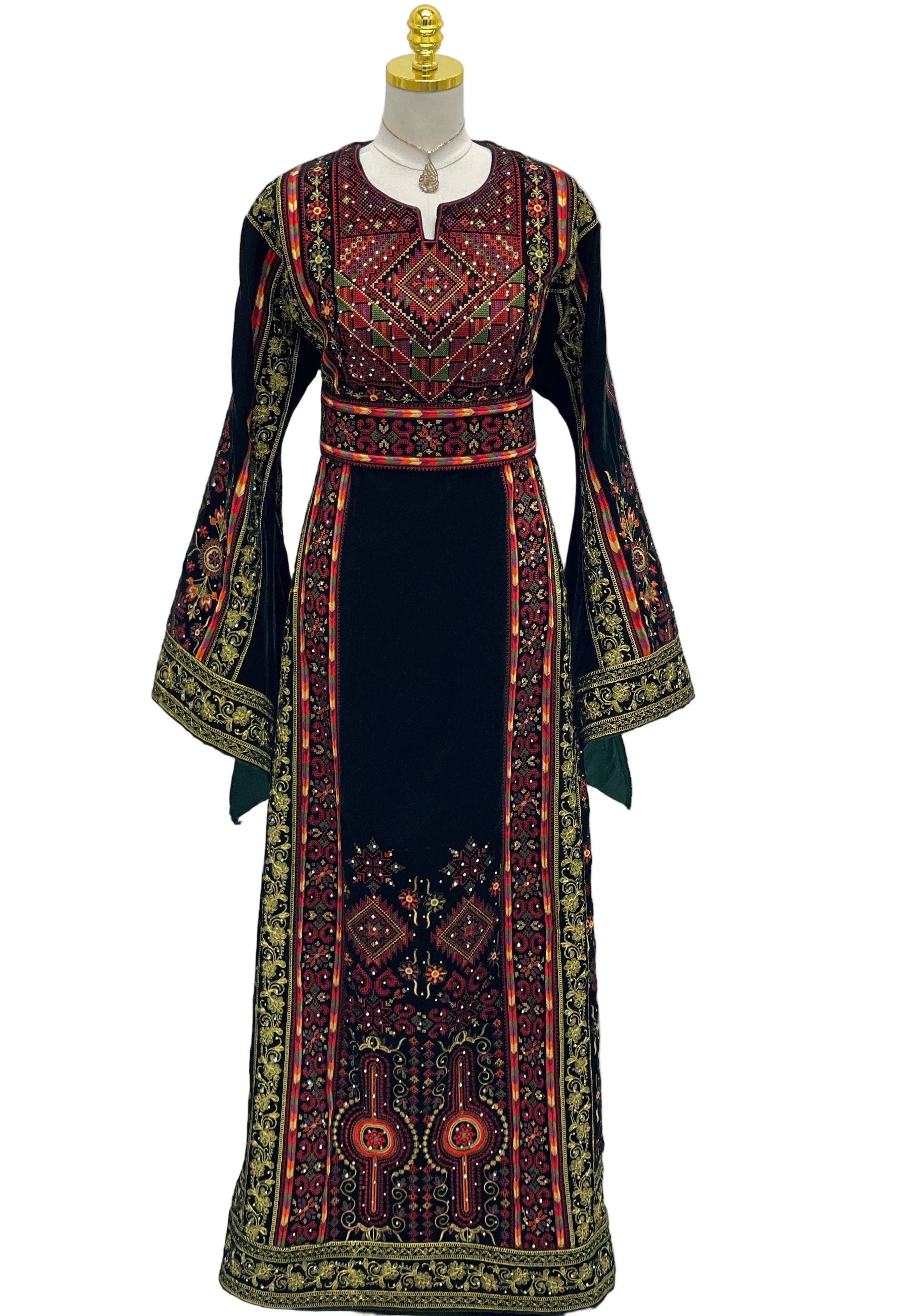 Decorative dress with intricate patterns on a mannequin against a white curtain background