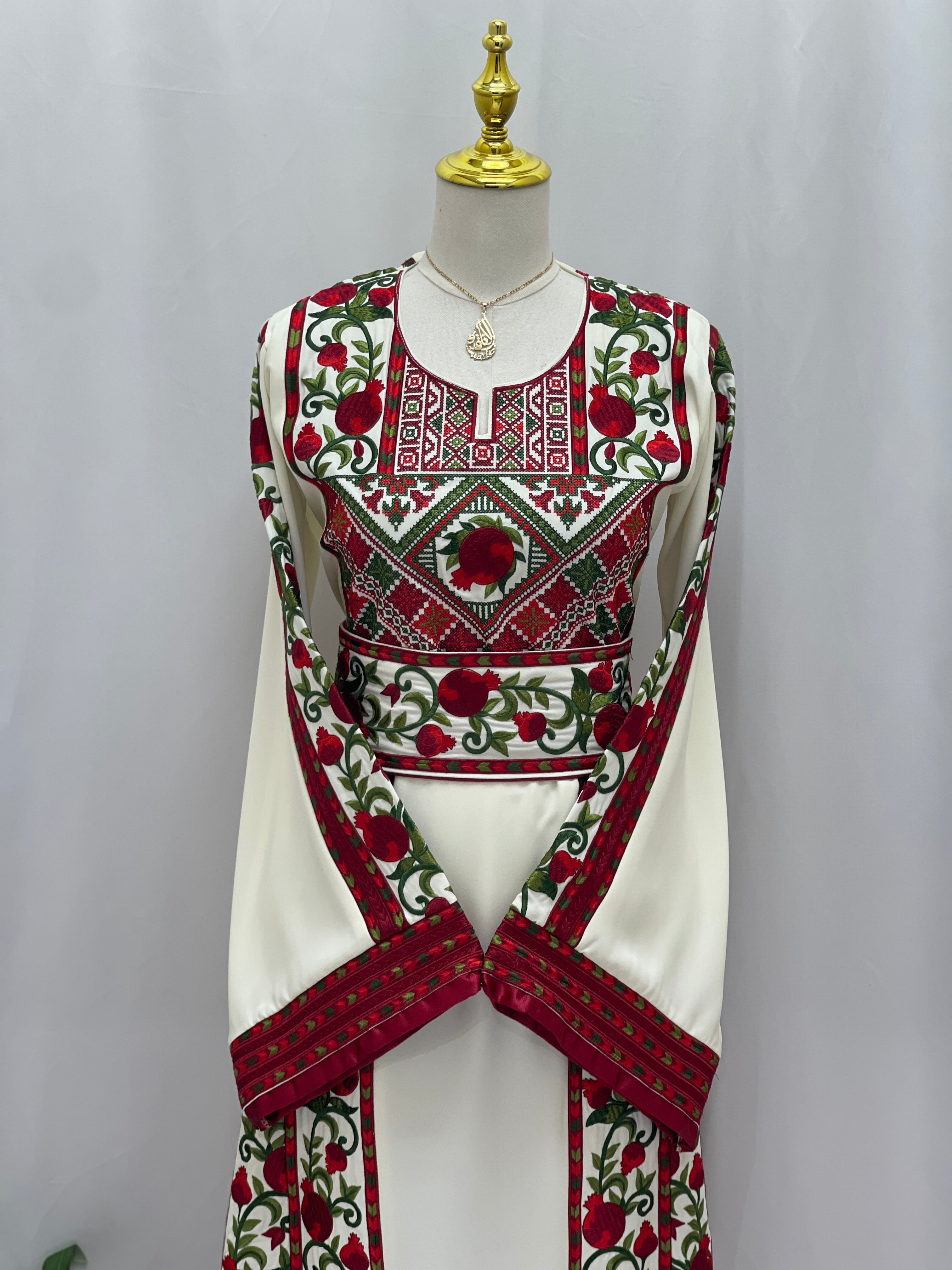 Al Romana Pomegranate Embroidered Thoub by Palestinian Elegance featuring intricate red and green embroidery on white fabric