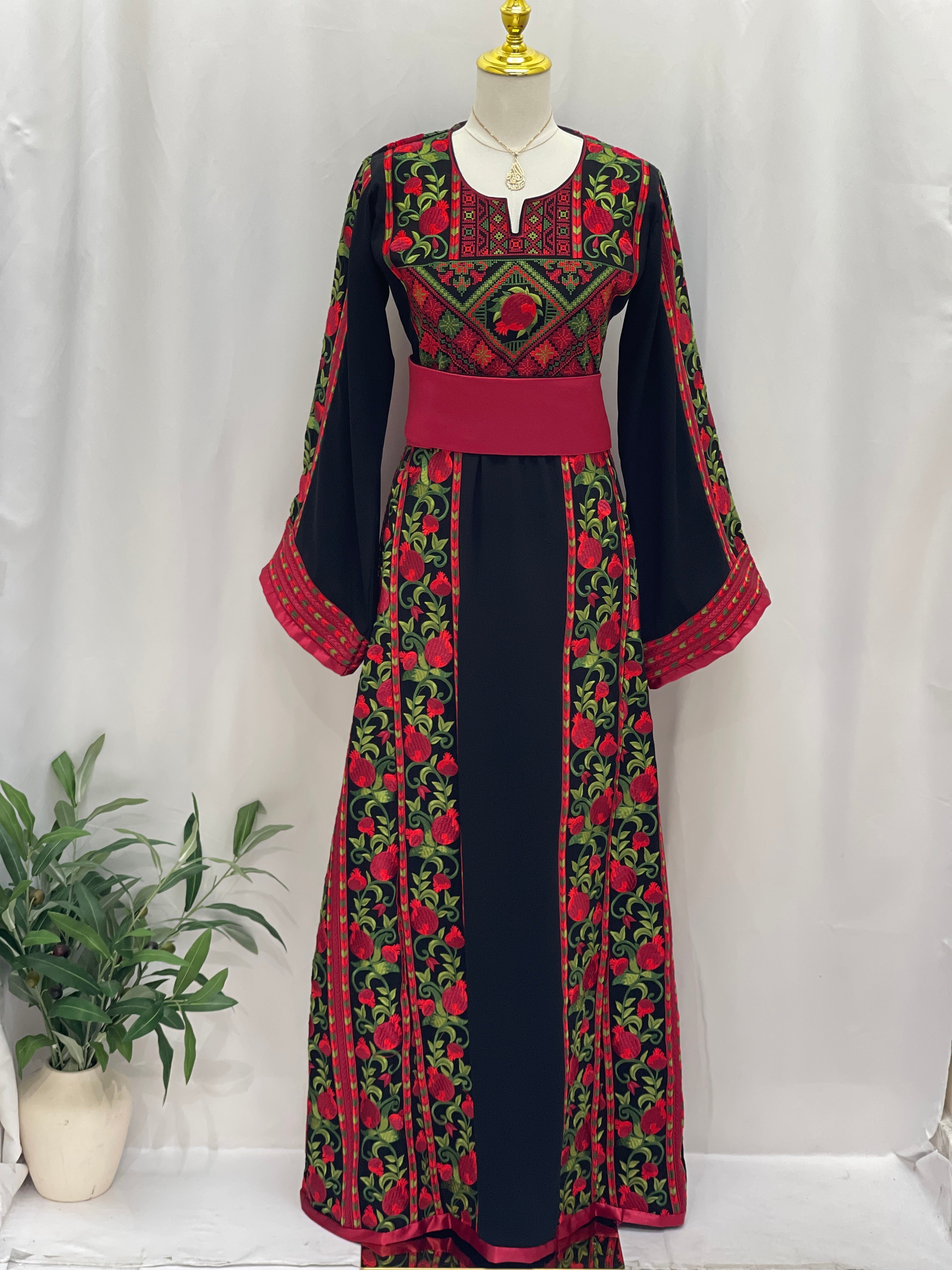 Al Romana Pomegranate Embroidered Thoub by Palestinian Elegance featuring black fabric with red and green pomegranate embroidery and wide sleeves