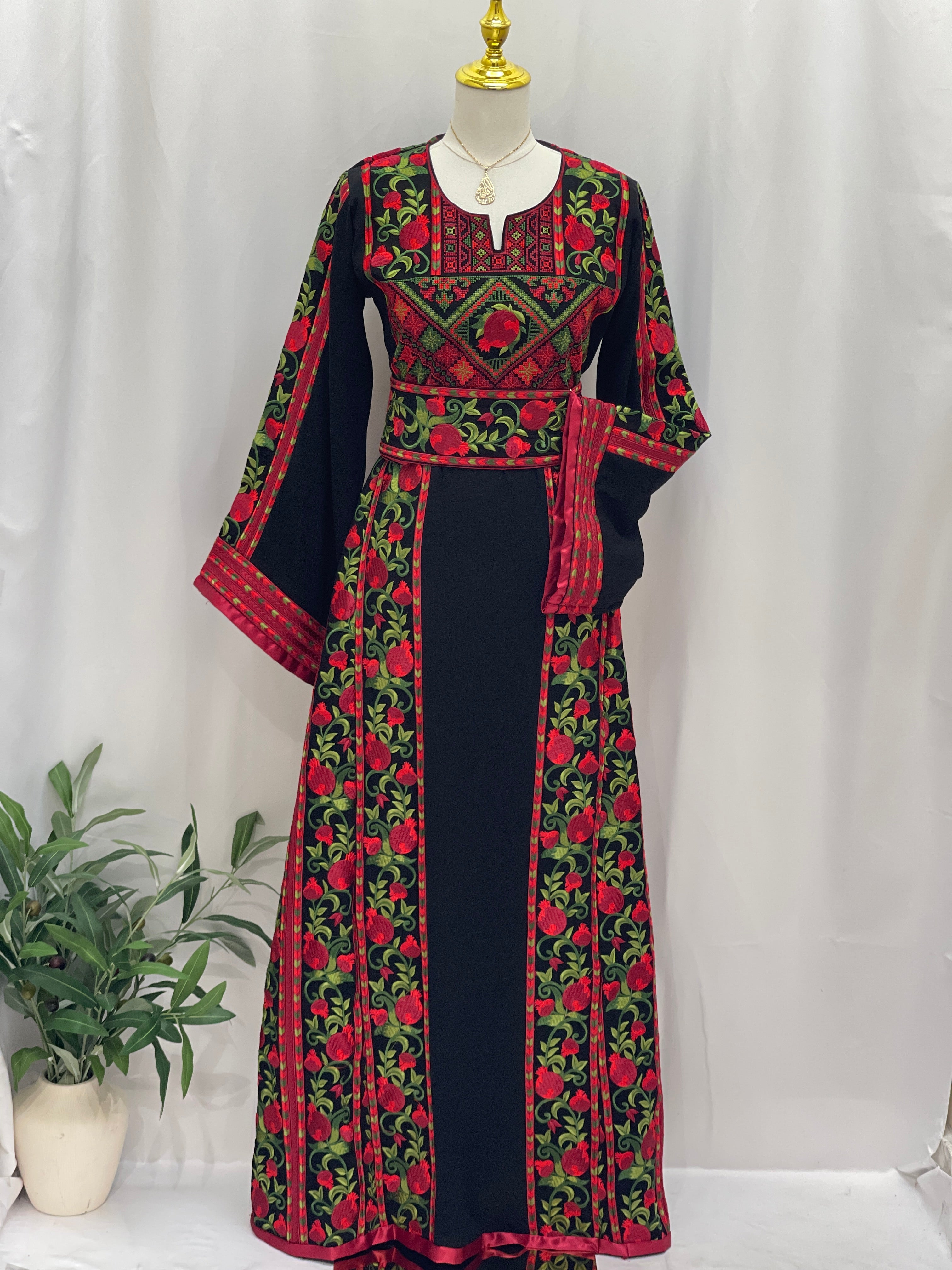 Al Romana Pomegranate Embroidered Thoub by Palestinian Elegance with intricate red and green floral patterns on black fabric