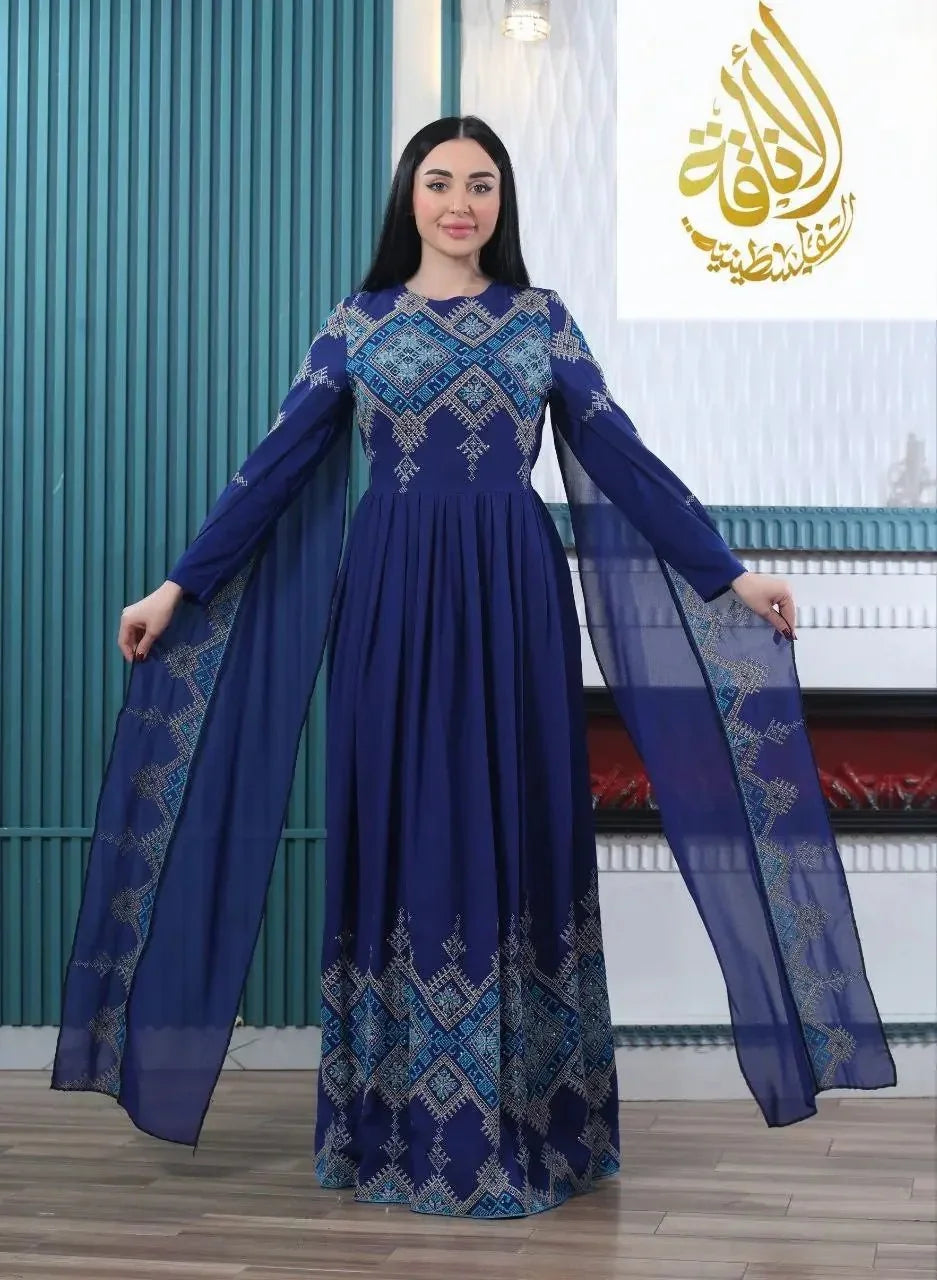 Woman wearing a modern embroidered Palestinian dress in blue with intricate geometric embroidery and flowing sheer sleeves