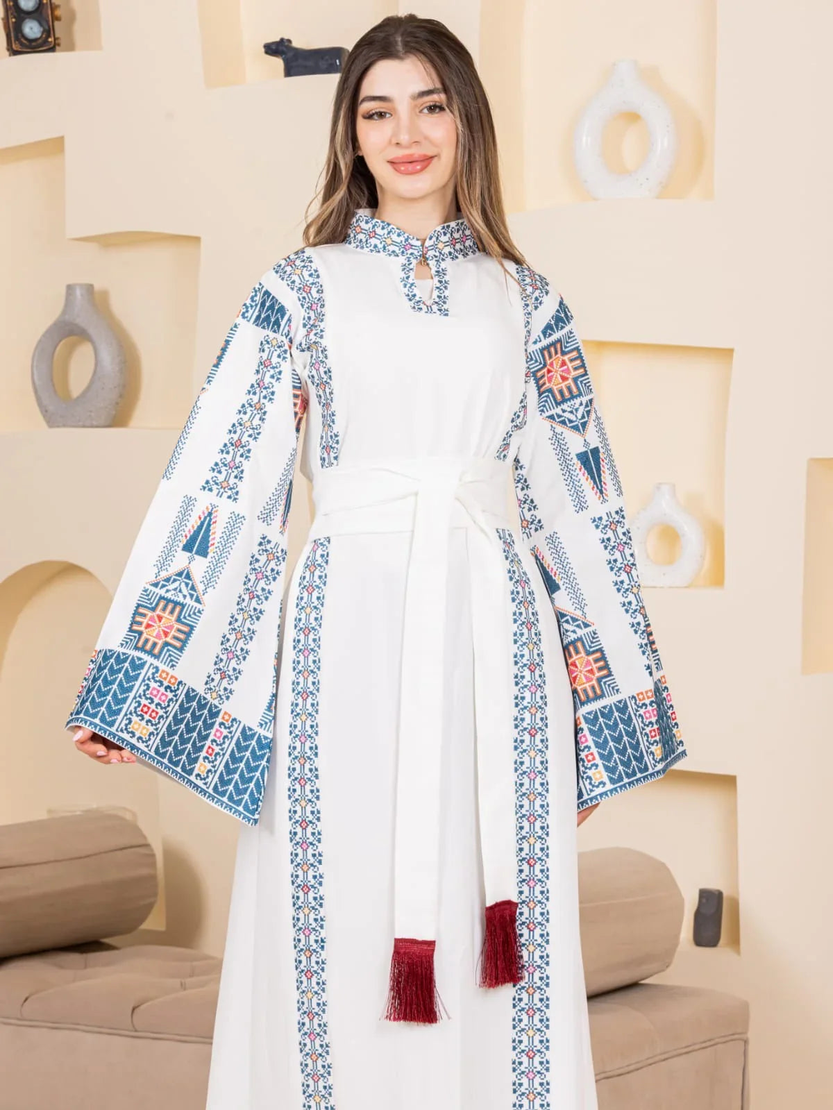 Asala Embroidered Thoub by Palestinian Elegance white embroidered thobe with blue red motifs and tassel belt