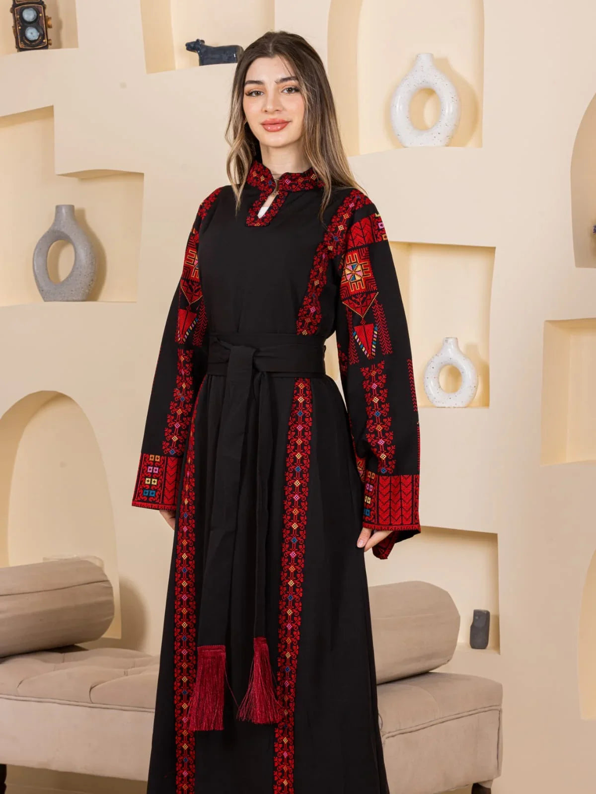 Woman wearing Asala Embroidered Thoub black with red Palestinian embroidery long sleeves belt tassels