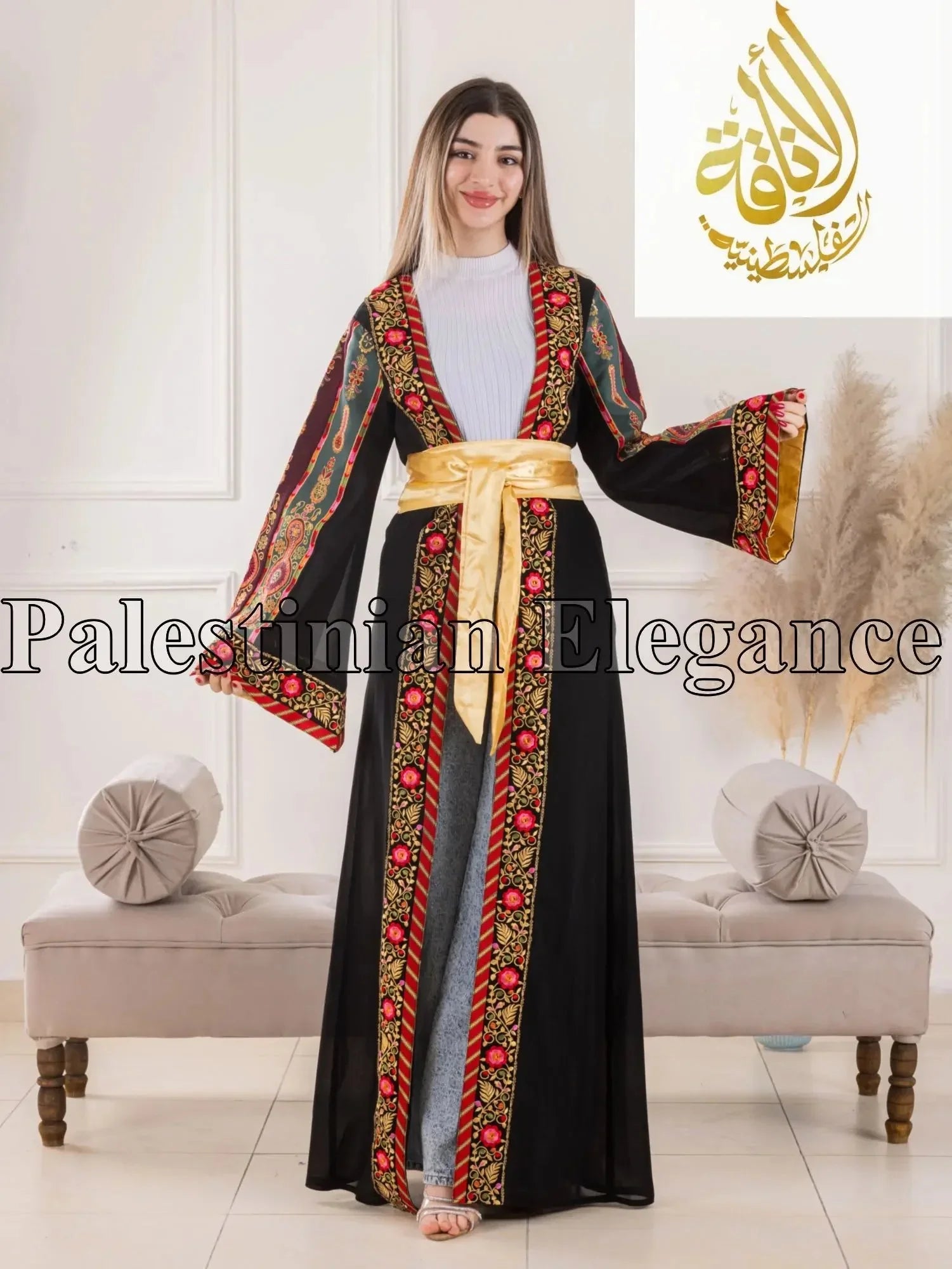 Aseel Malaka embroidered Cardigan by Palestinian Elegance with black fabric and red floral embroidery worn by a smiling woman