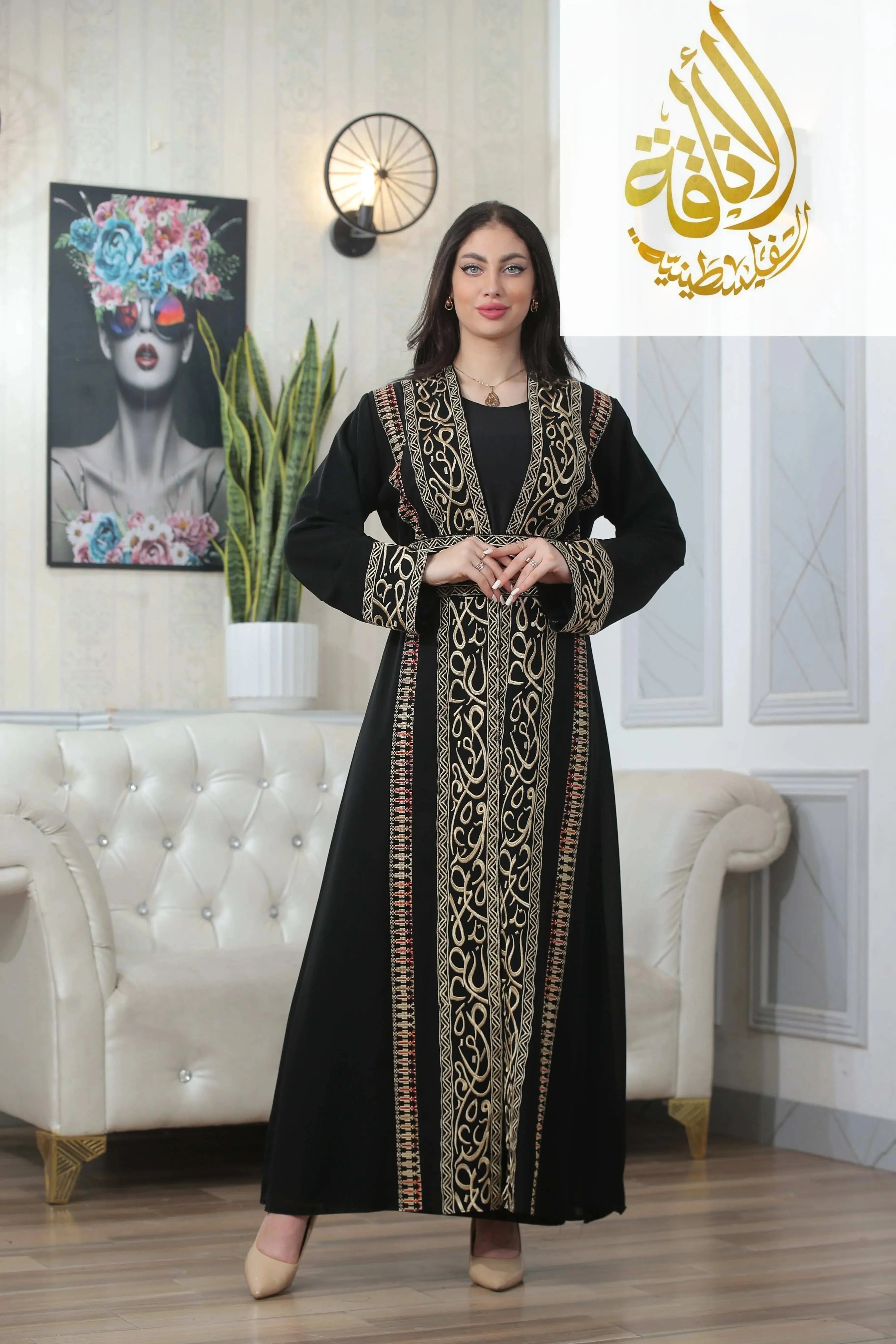 Black thoub by Palestinian Elegance with Basma Arabic letters with heritage embroidery Bisht design worn by a woman indoors