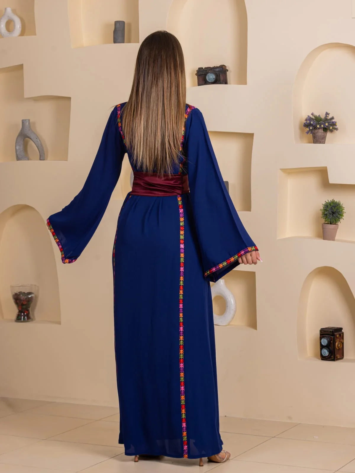 Blossom Embroidered Thobe by Palestinian Elegance navy blue back view with colorful embroidered trim and burgundy sash
