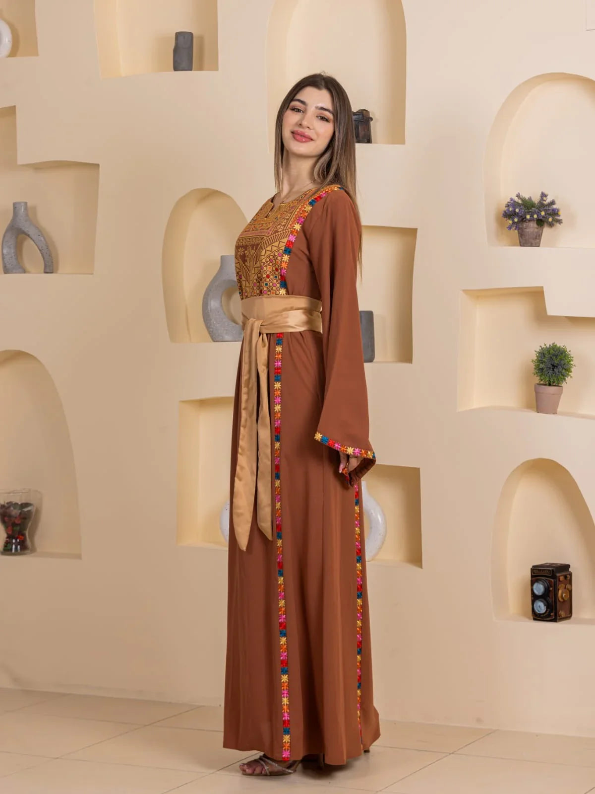 Blossom Embroidered Thobe by Palestinian Elegance brown gown with gold sash colorful floral embroidery on front and cuffs