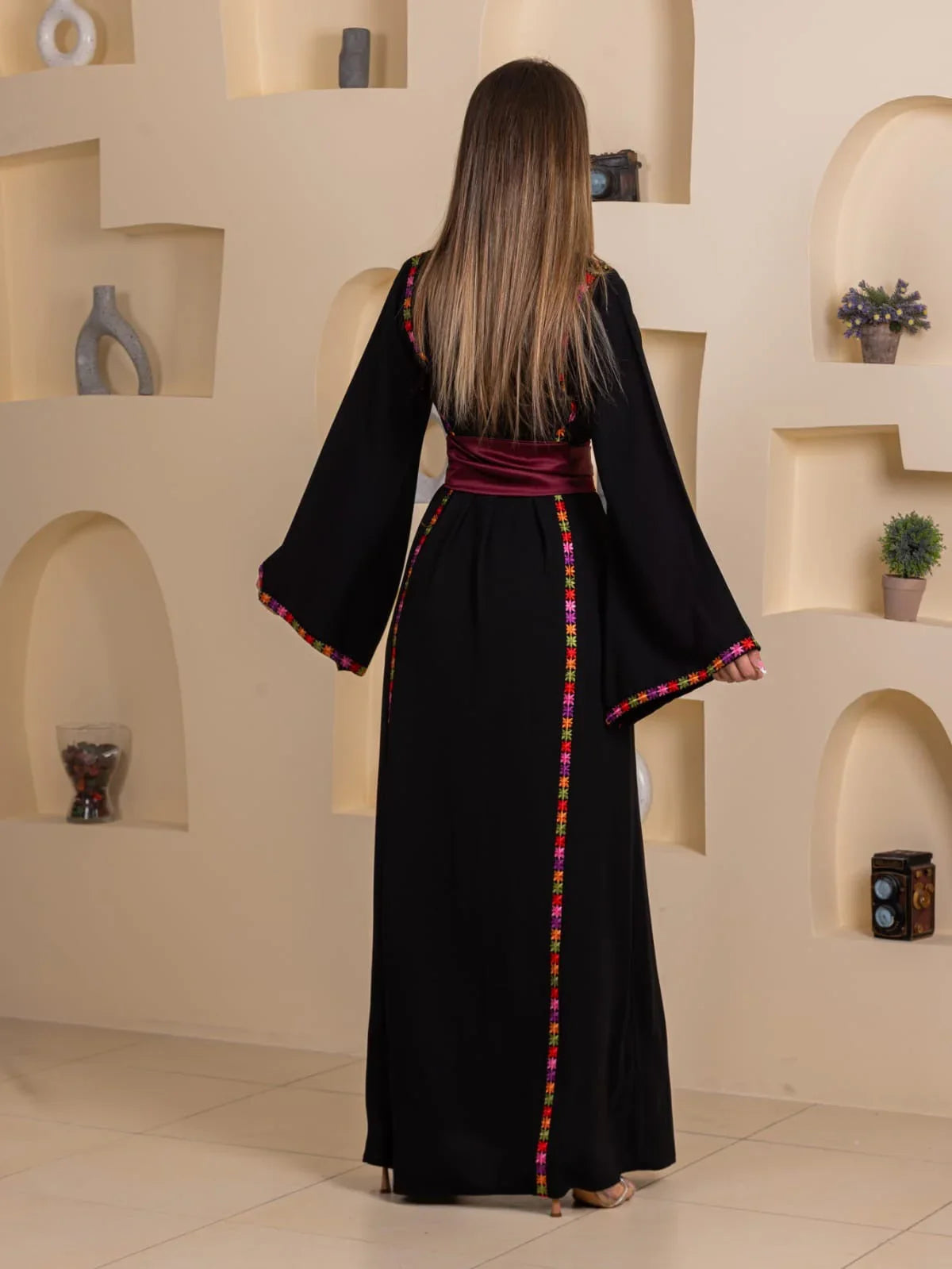 Blossom Embroidered Thobe black floor length back view with colorful Palestinian embroidery trim and burgundy waist sash