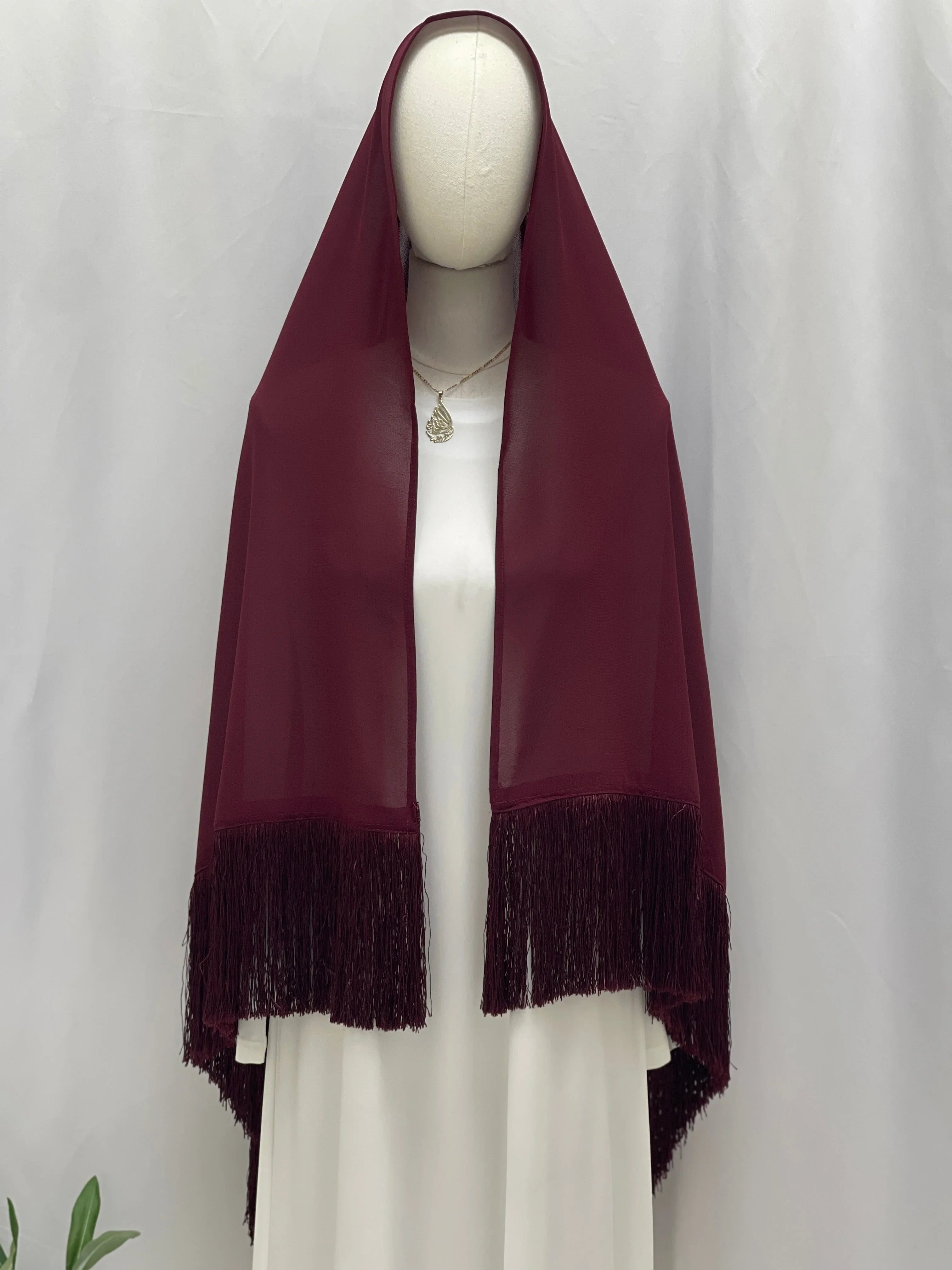Dark Maroon Khirka With Tassel draped on mannequin over white dress showing long fringe hem by Palestinian Elegance