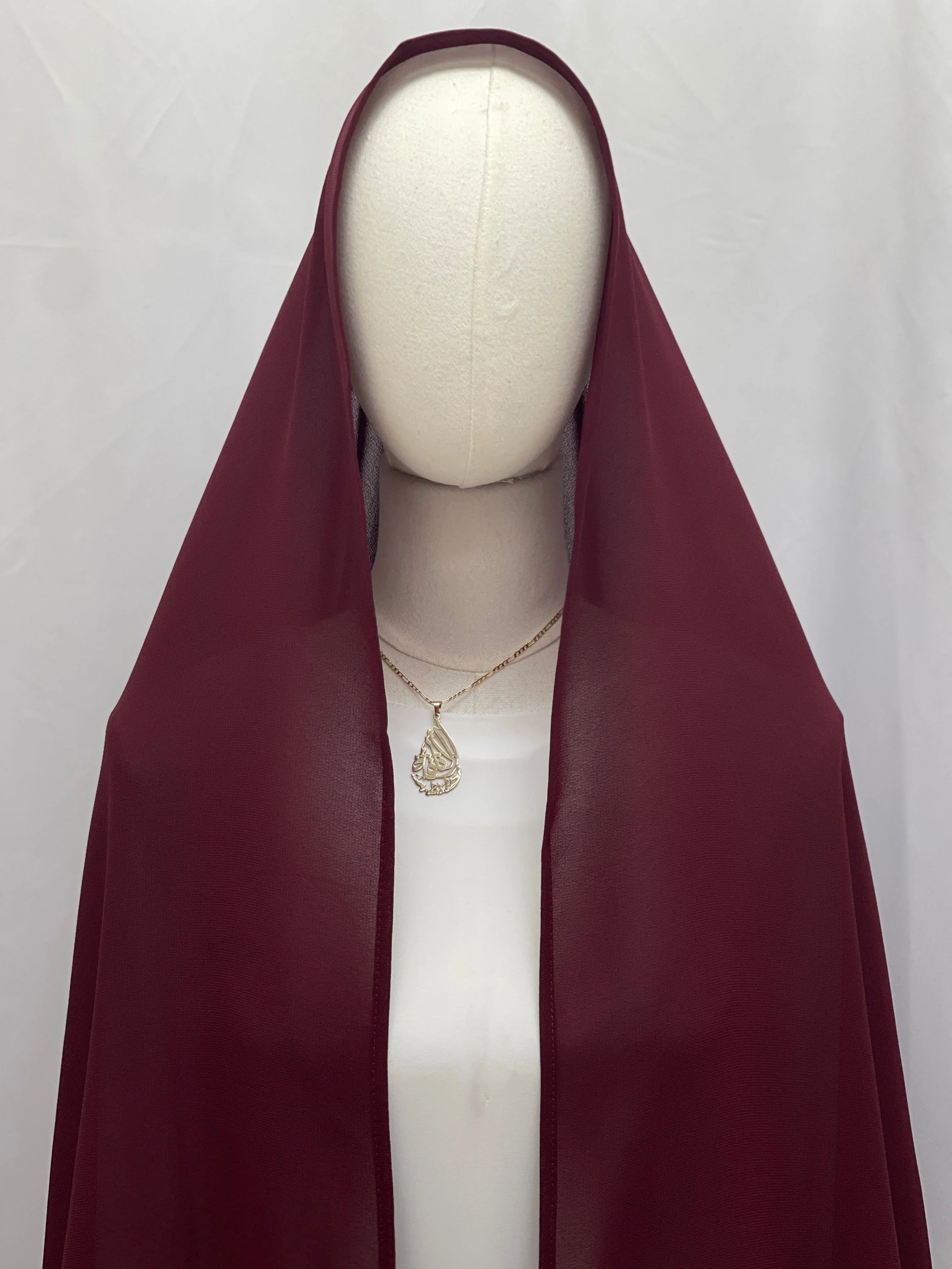 Dark Maroon Khirka With Tassel by Palestinian Elegance displayed on mannequin draped over white dress with simple gold pendant
