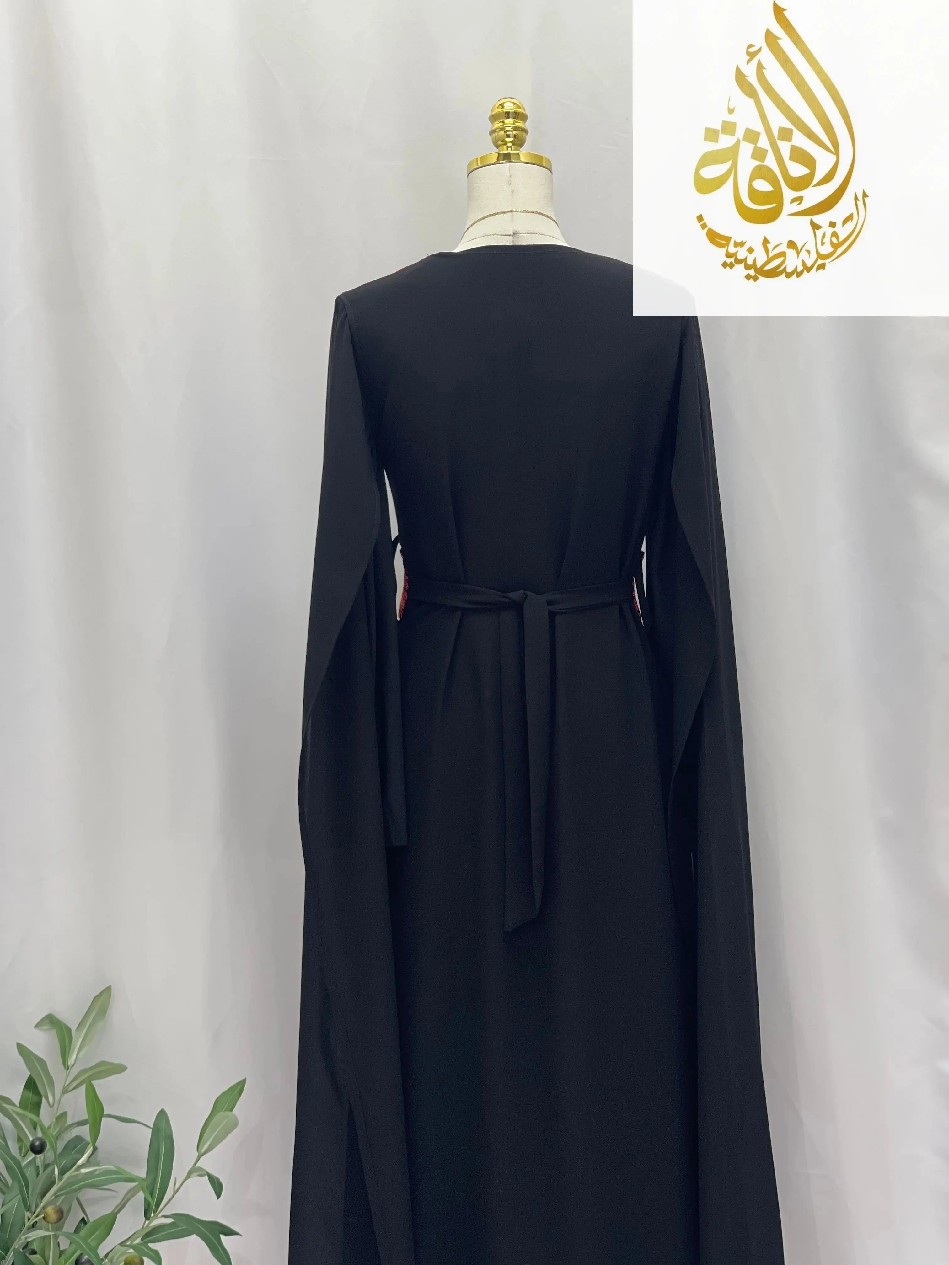 Back view of a black embroidered Palestinian dress with long sleeves and a waist tie from Palestinian Elegance