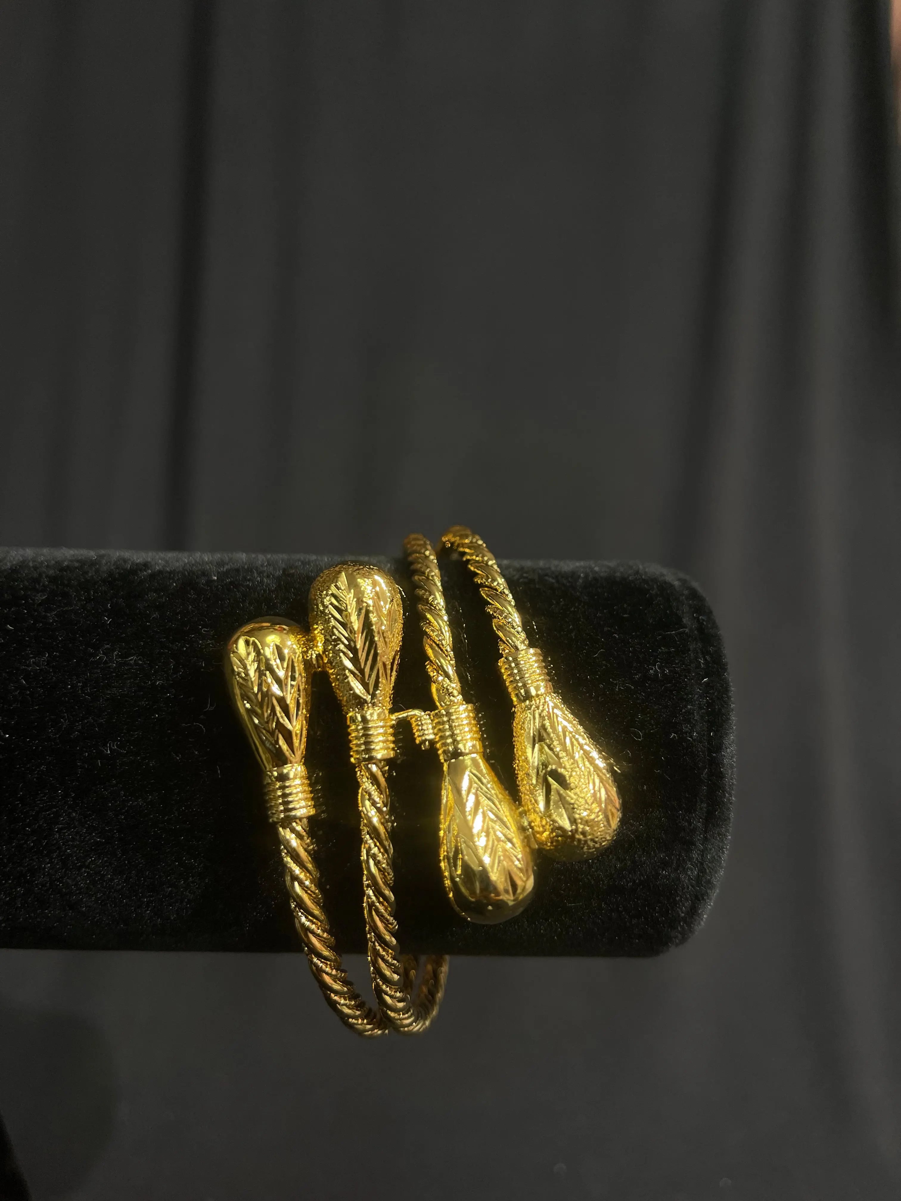 Imitated Palestinian gold bangle bracelet with intricate twisted design on black display