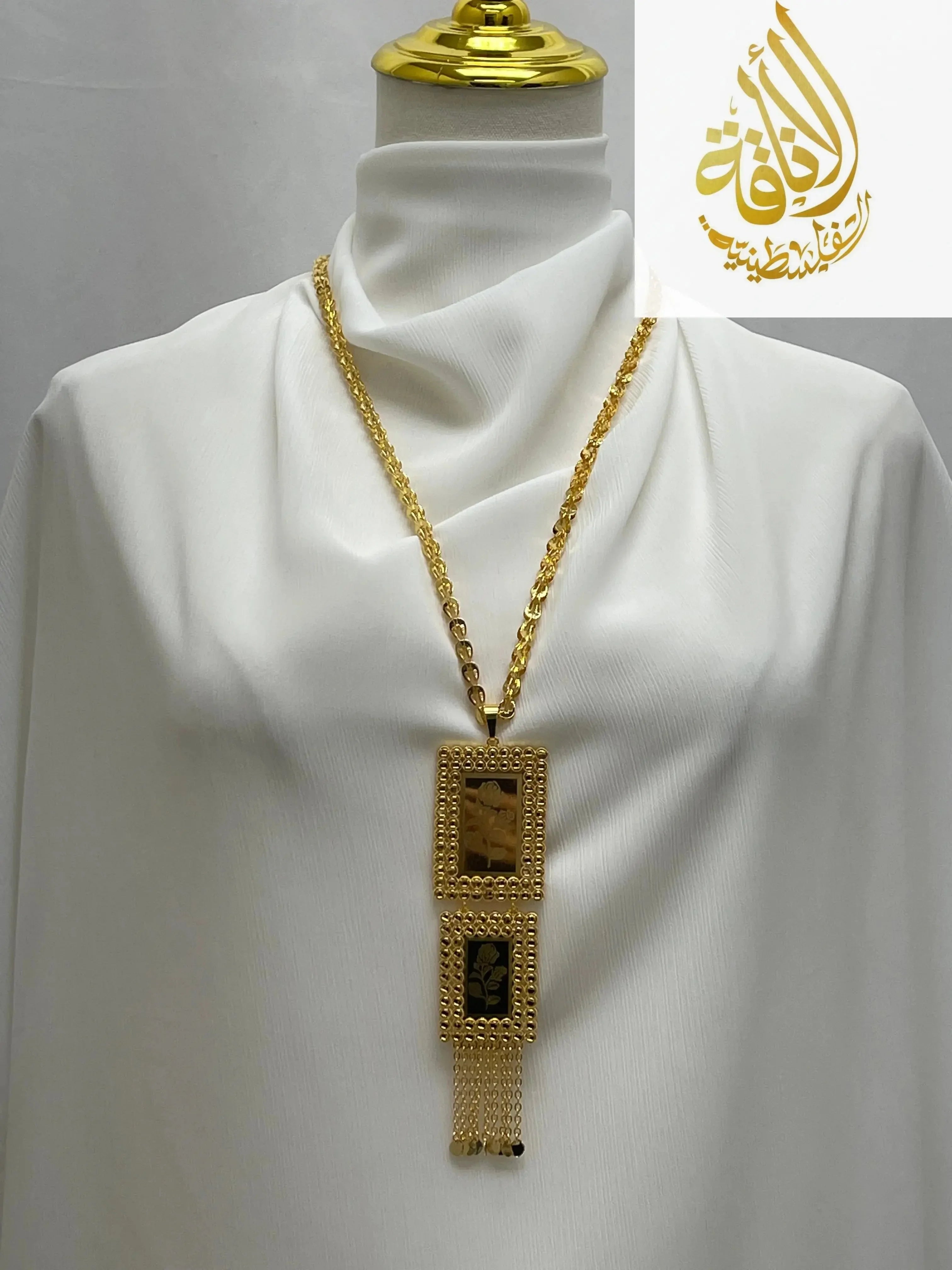 Palestinian embroidered gold necklace with rectangular pendants and chain tassels displayed on white fabric