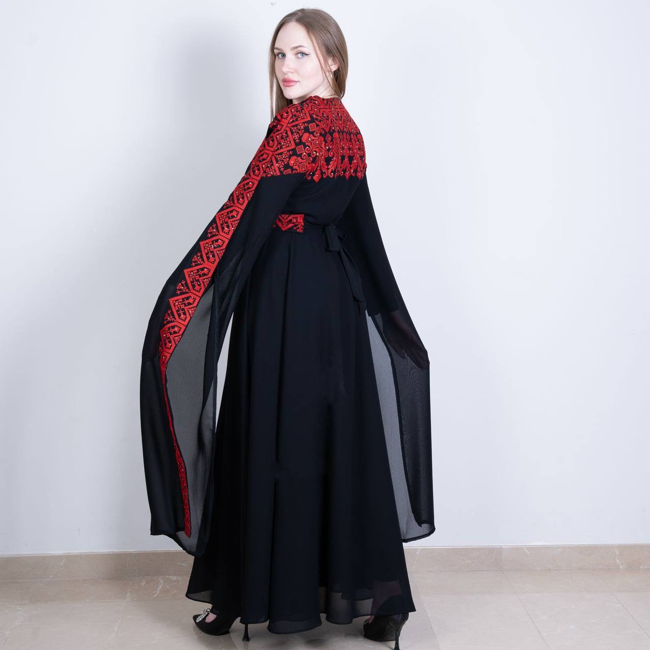 Palestinian embroidered dress by Palestinian Elegance featuring black fabric with intricate red embroidery on sleeves and shoulders