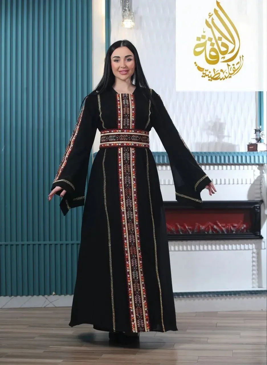 Woman wearing a black embroidered Palestinian kaftan with traditional red and white patterns from Palestinian Elegance