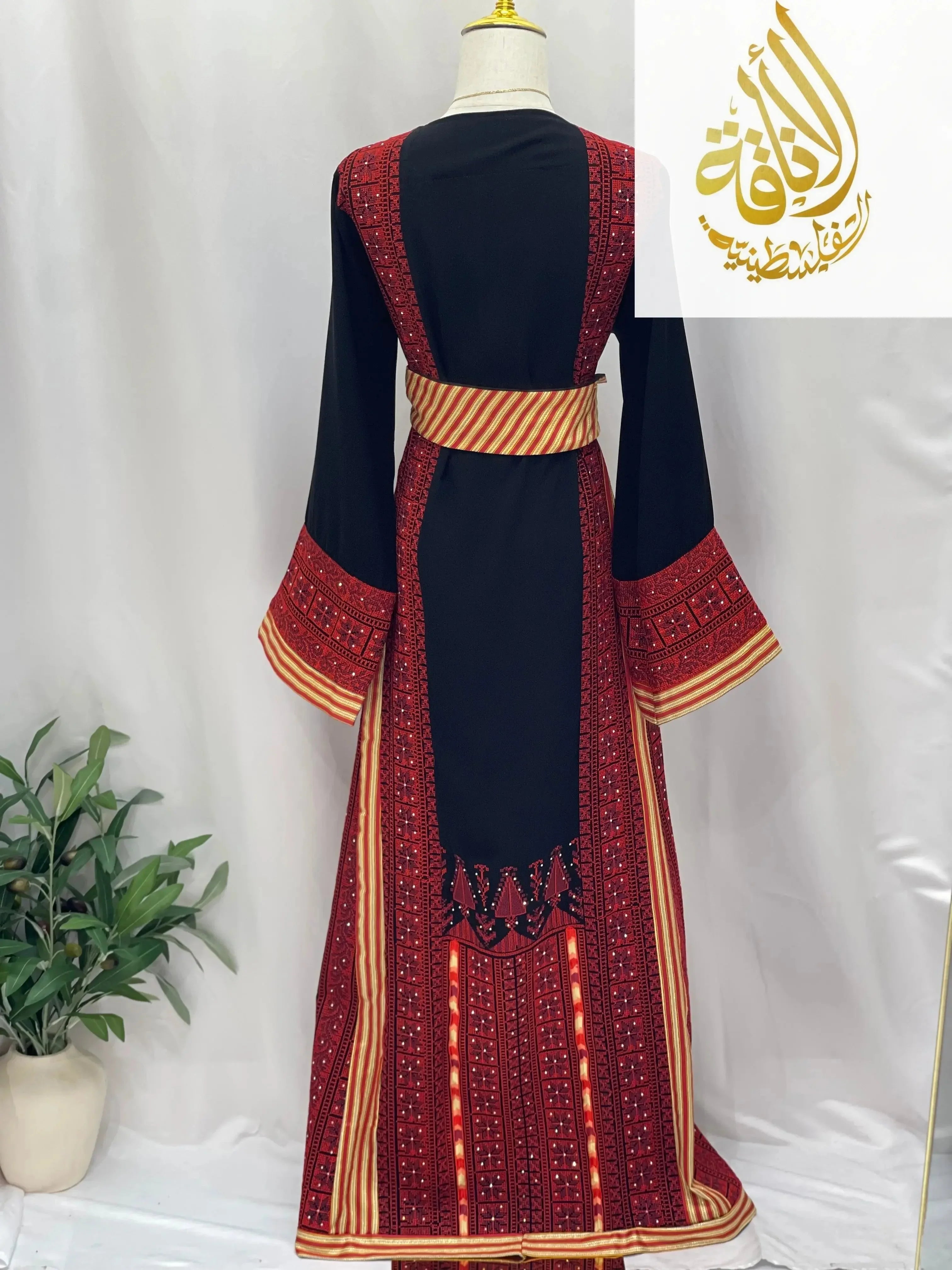 Embroidered Palestinian thoub dress in black with red traditional embroidery and striped waist sash by Palestinian Elegance