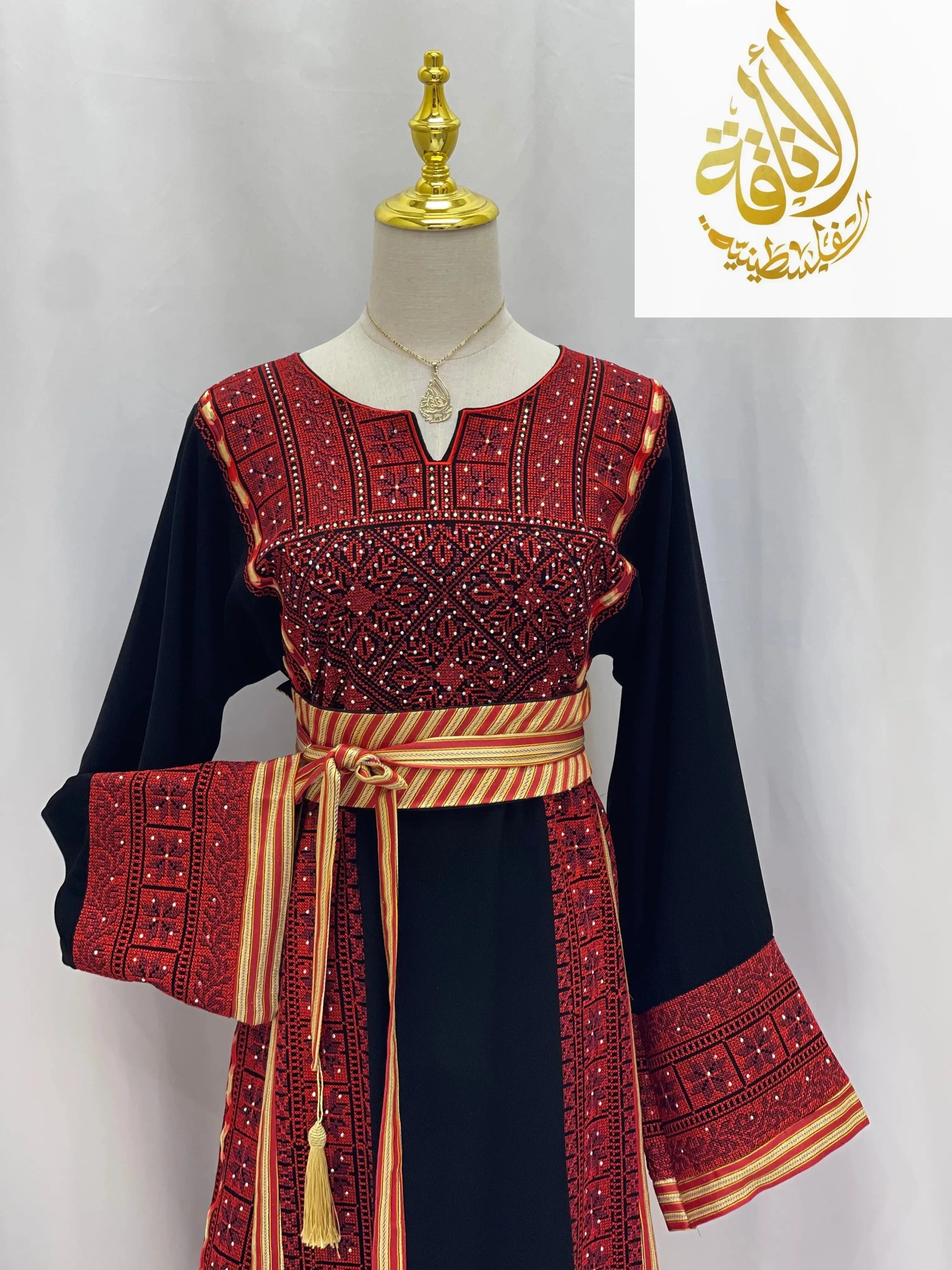 Embroidered Palestinian thoub dress with intricate red embroidery and a striped waist sash from Palestinian Elegance