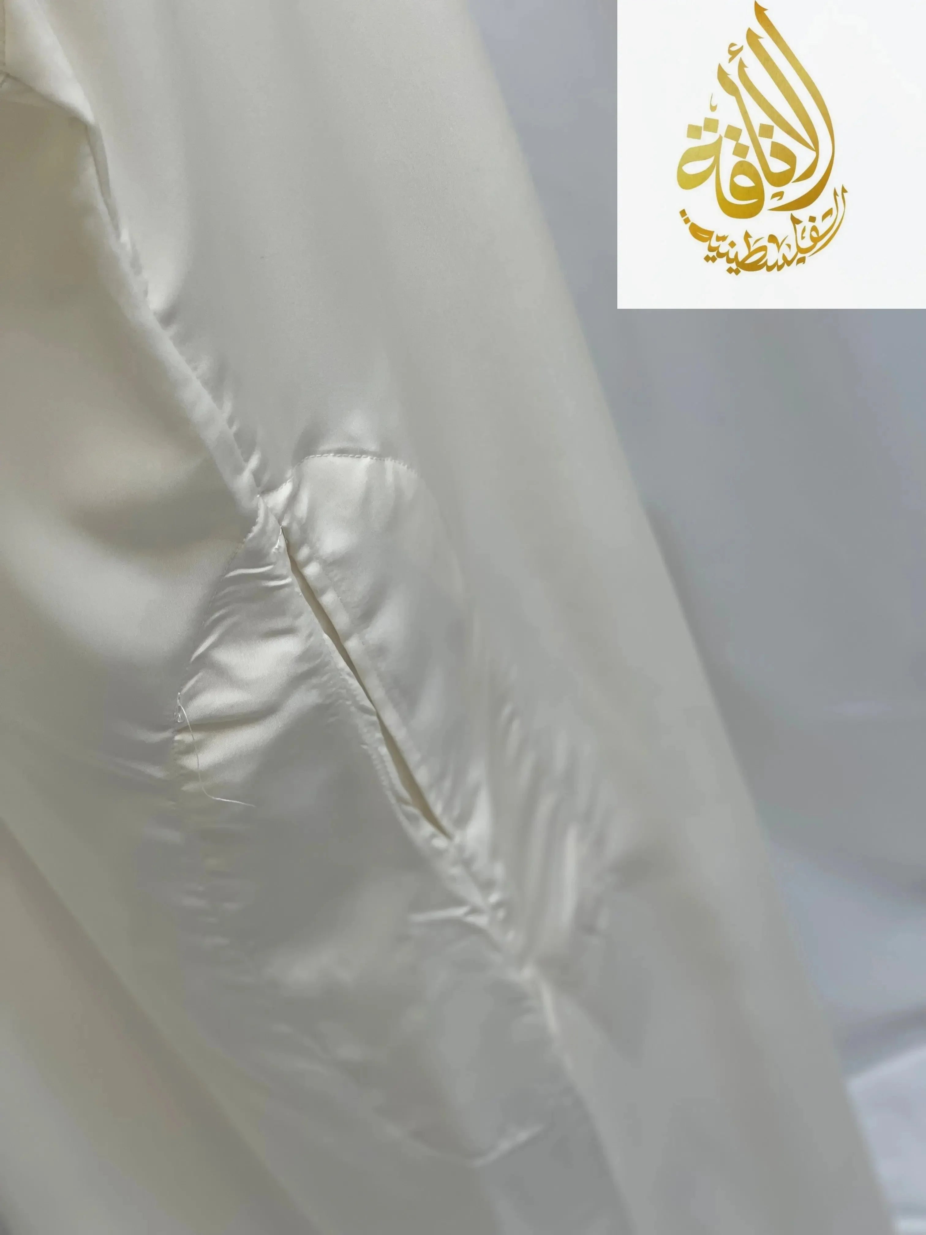 Close-up of a white embroidered thobe dress by Palestinian Elegance showing detailed stitching on smooth fabric