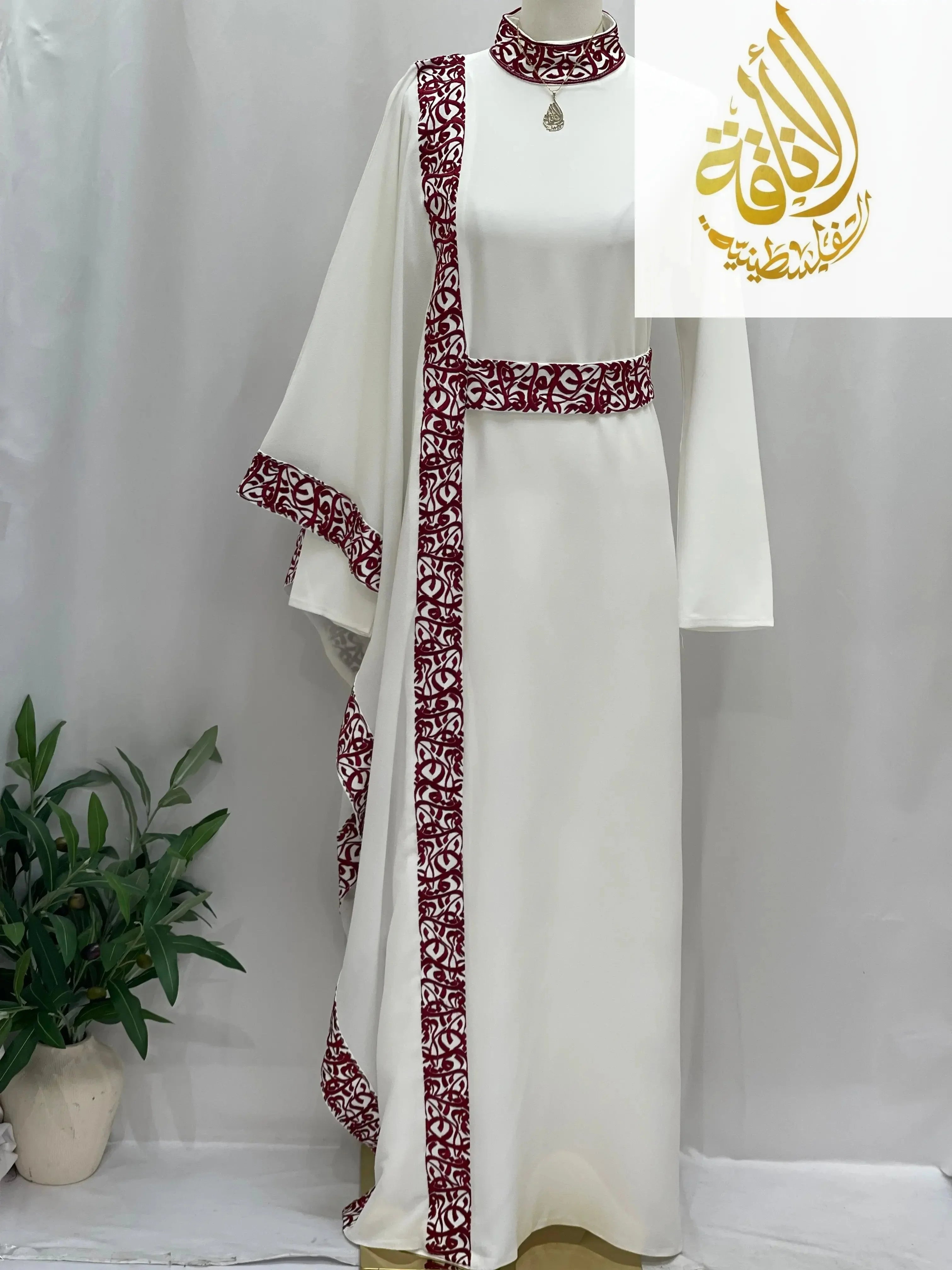White embroidered abaya with Arabic letters and maroon decorative trim by Palestinian Elegance