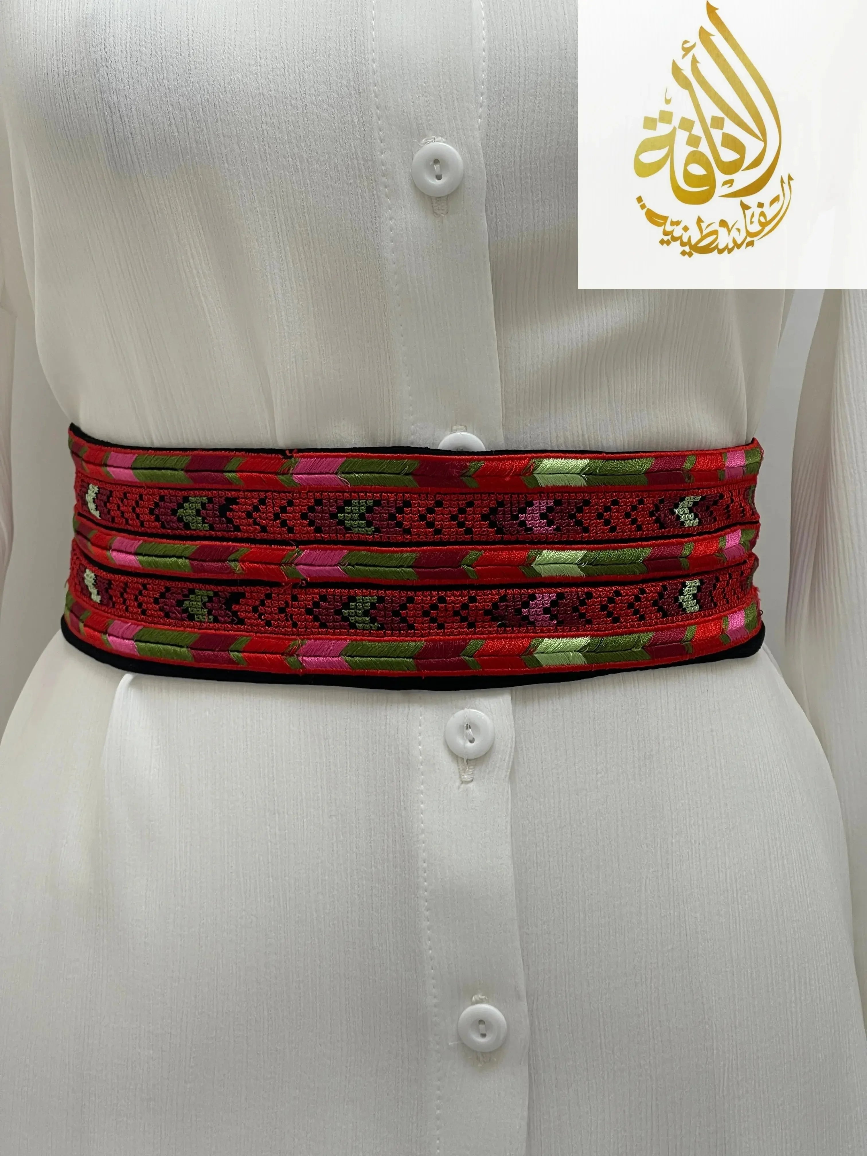 Palestinian Elegance Embroidered Heritage Belt in red with green and pink accents wrapped around white dress waist