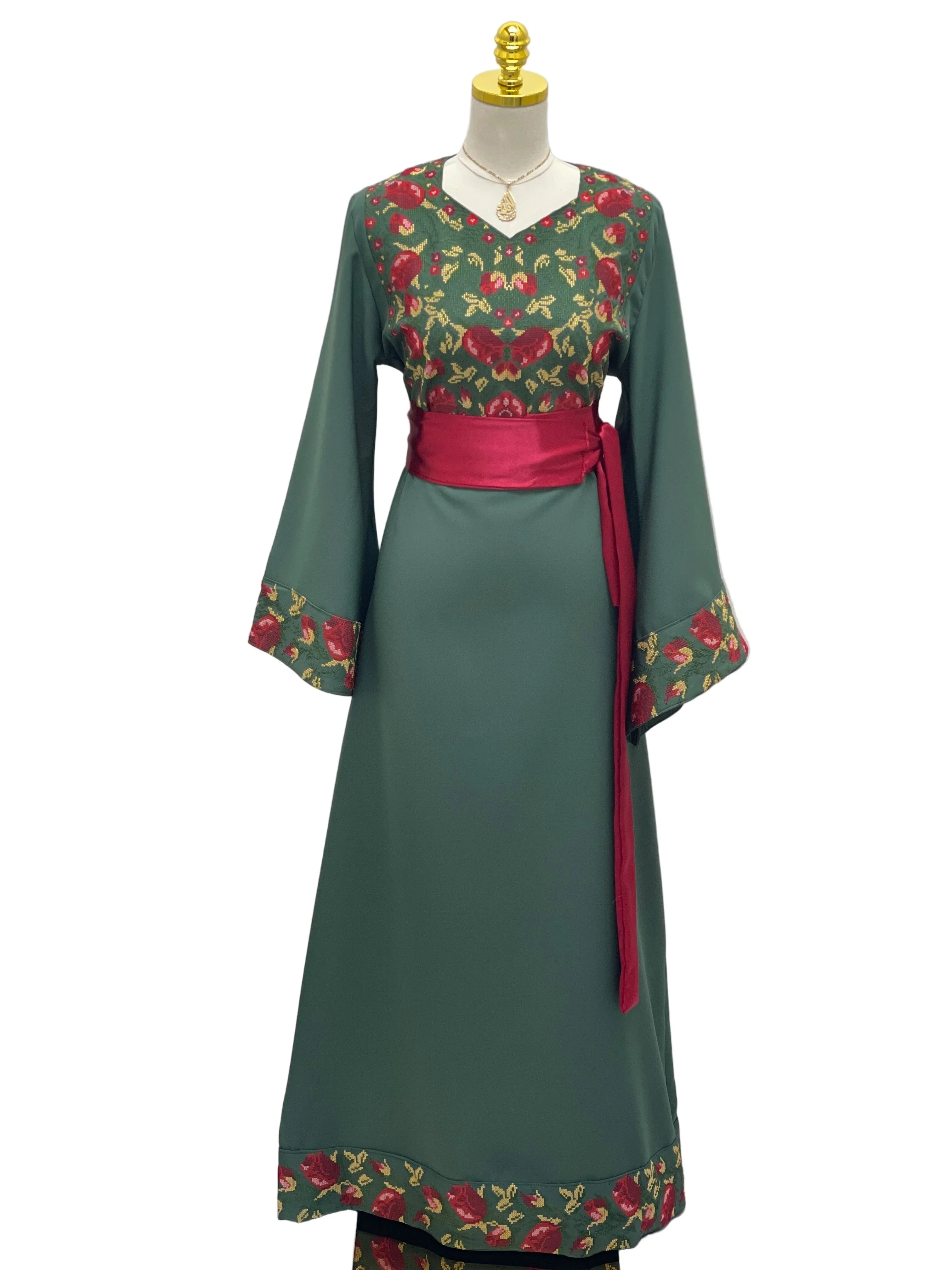 Emerald Blossom EmbroideredThobe by Palestinian Elegance green embroidered thobe with red sash and floral chest cuff hem details