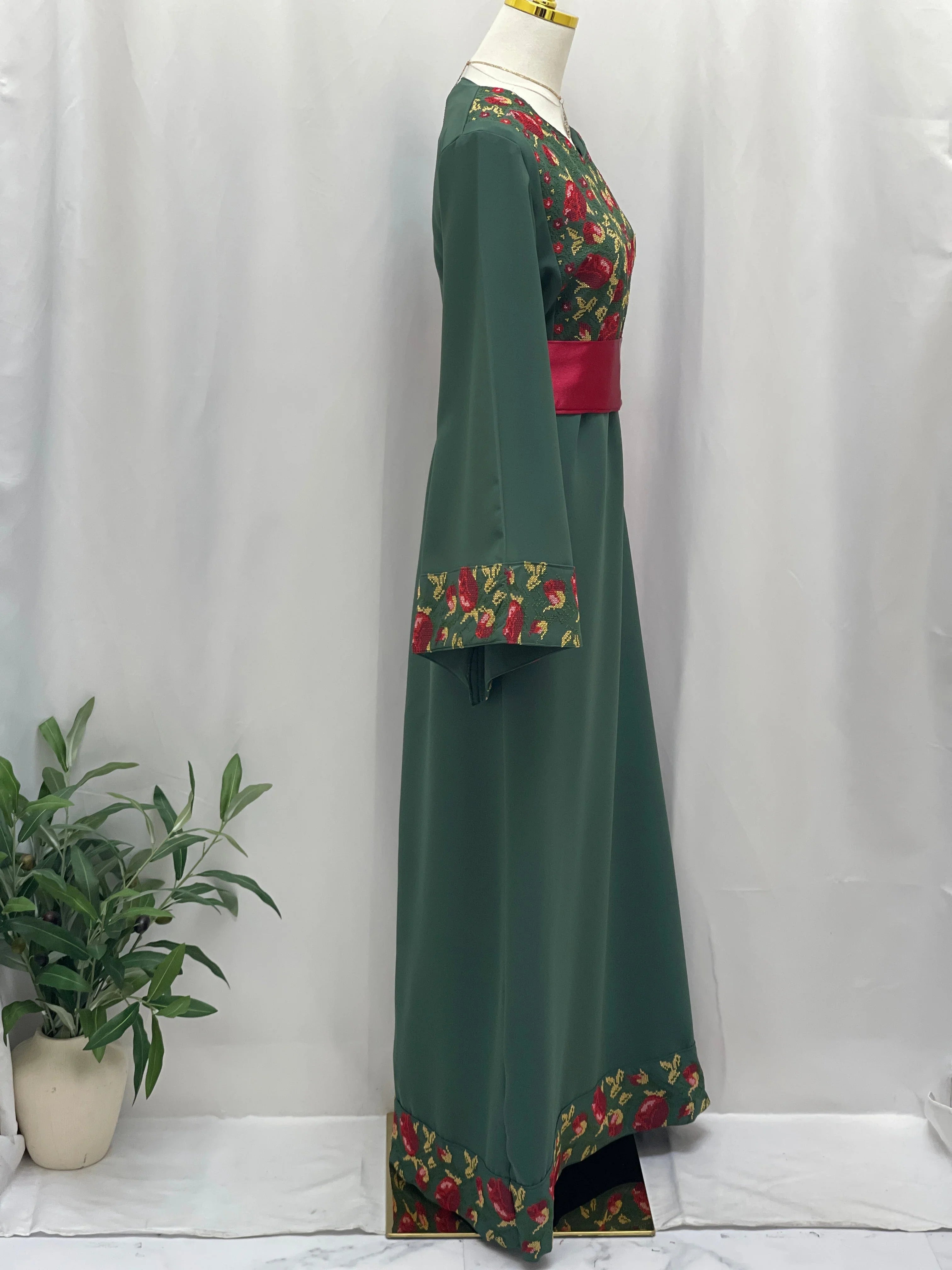 Emerald Blossom EmbroideredThobe by Palestinian Elegance green full length side view with red floral embroidery