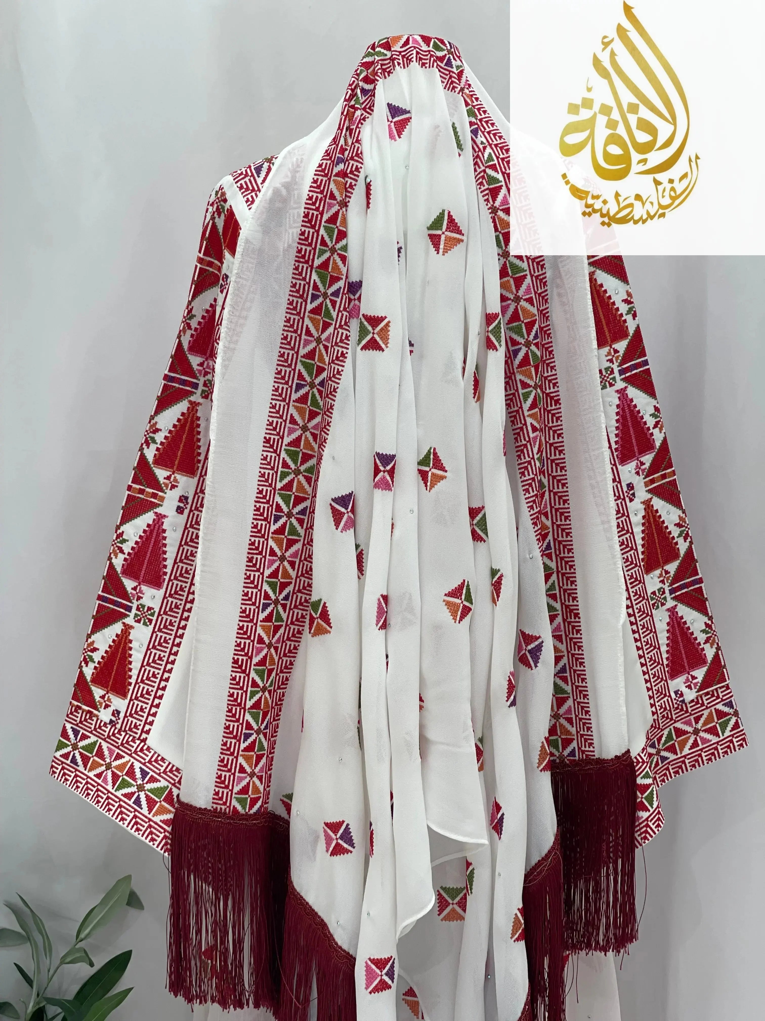 Palestinian Elegance embroidered Falahi thoub with overskirt featuring traditional red and white geometric patterns and fringe details