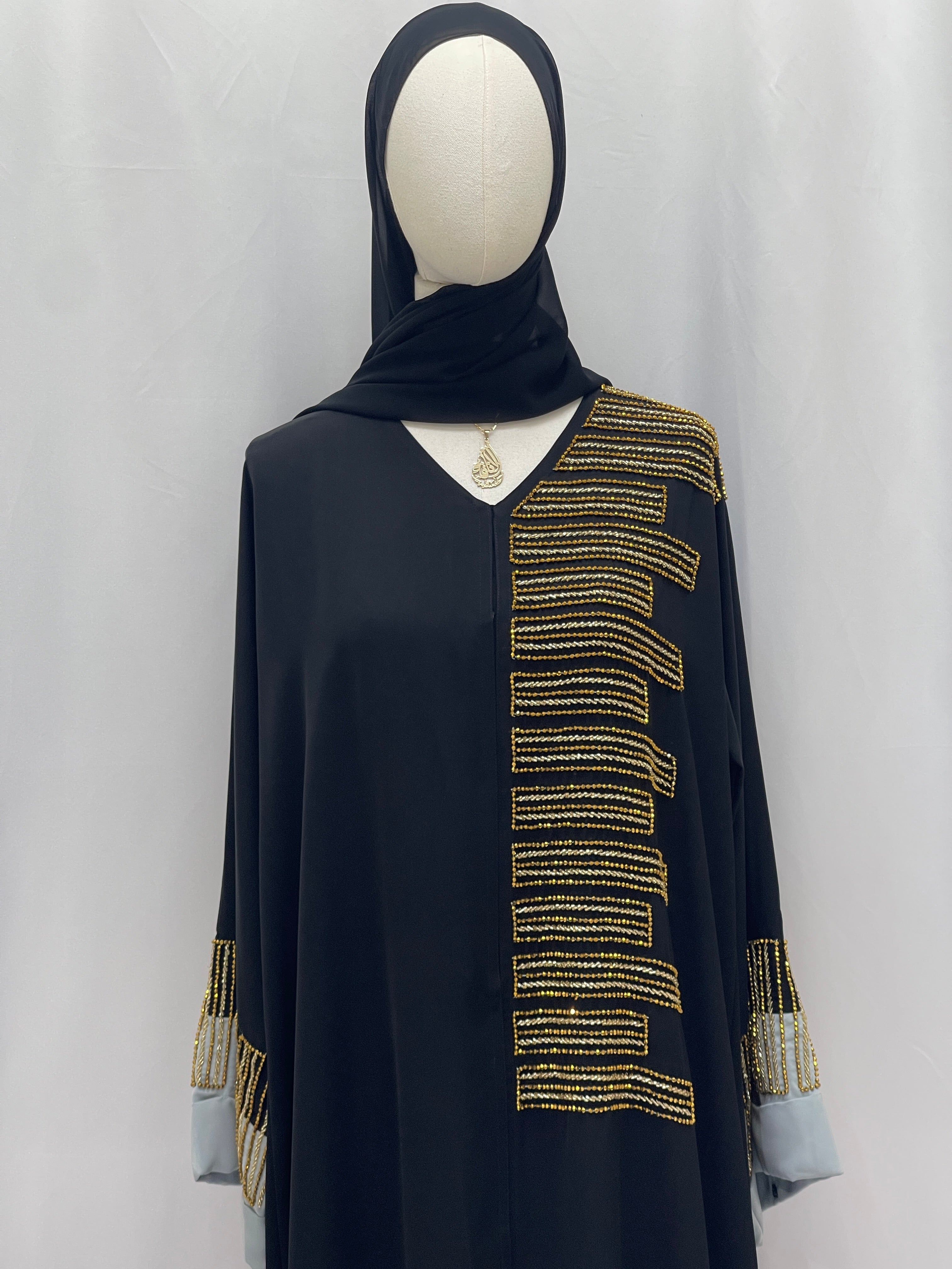 Palestinian Elegance Fancy Beads Dubai Abaya black abaya on mannequin with gold bead embellishments on front and cuffs