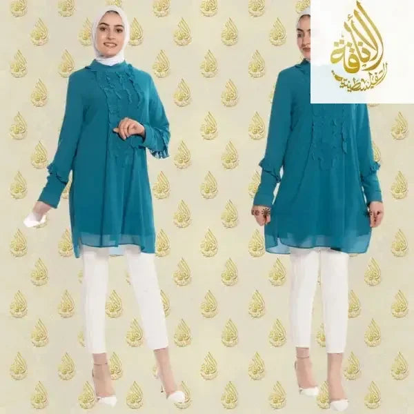 Luxury women's embroidered shirt in teal blue by Palestinian Elegance paired with white pants and white heels