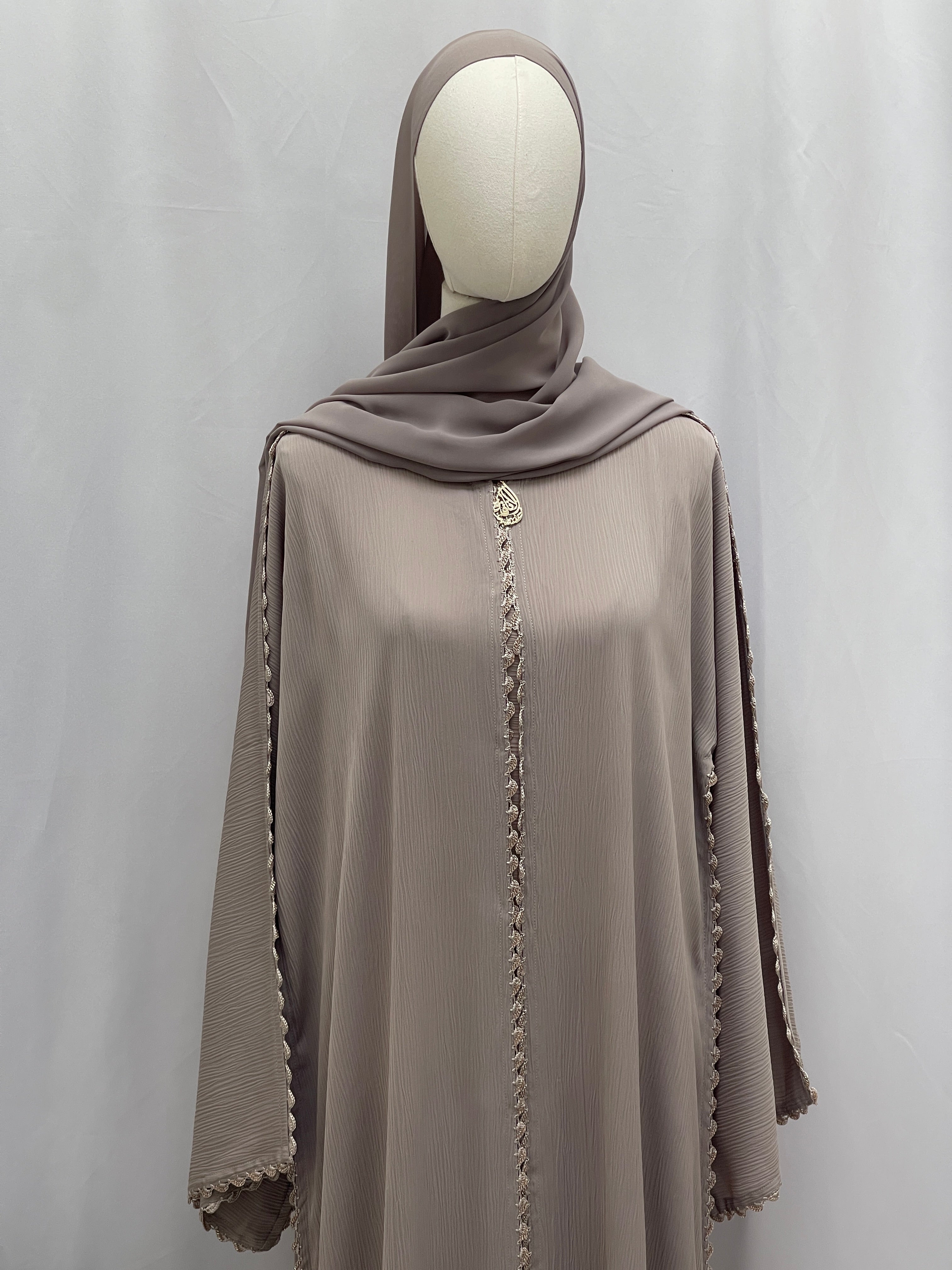 Palestinian Elegance Ghosoon Abaya in taupe with intricate trim on front and sleeves displayed on mannequin