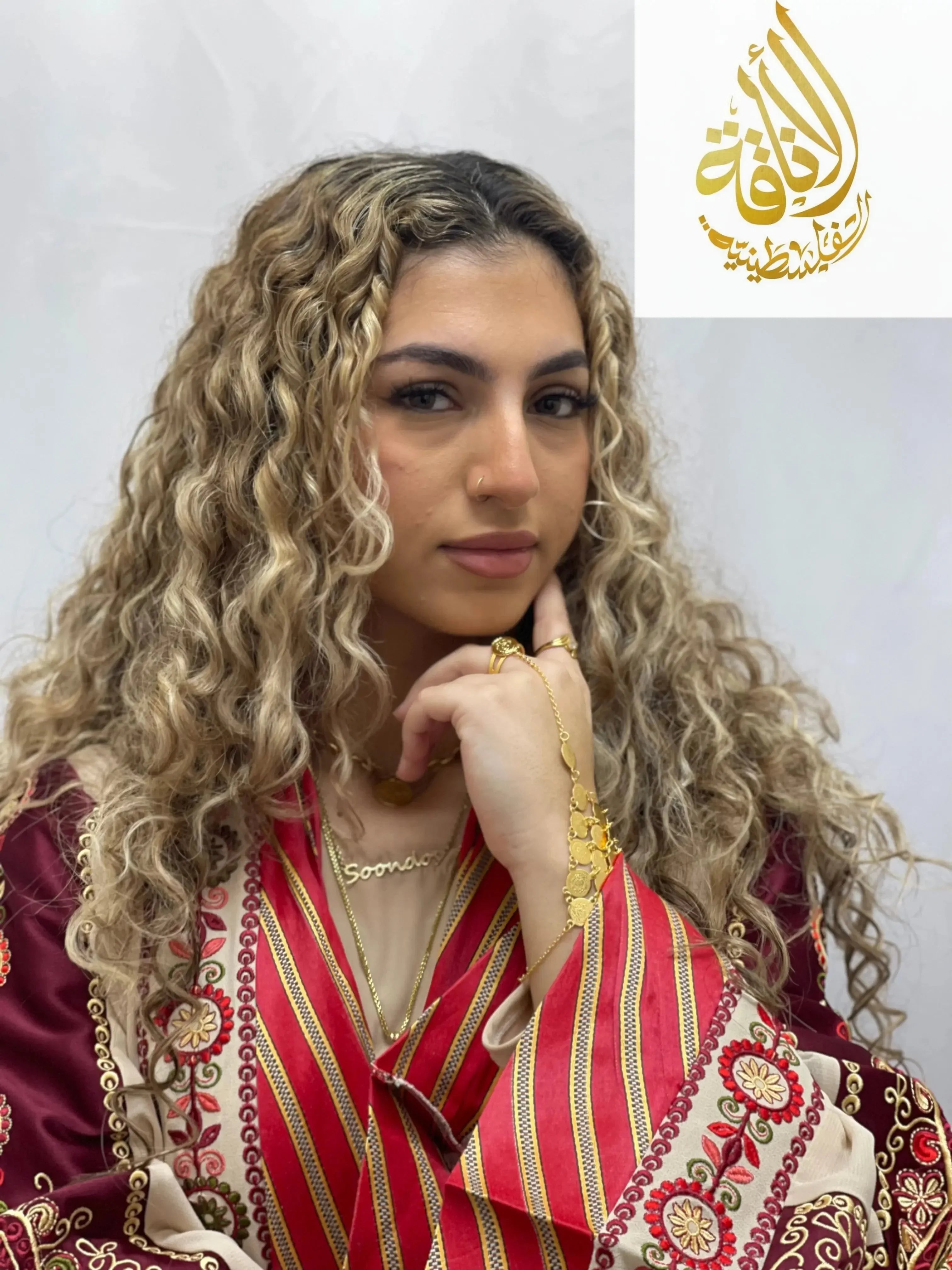 Woman wearing Palestinian Elegance gold kaff hand jewelry with traditional embroidered attire