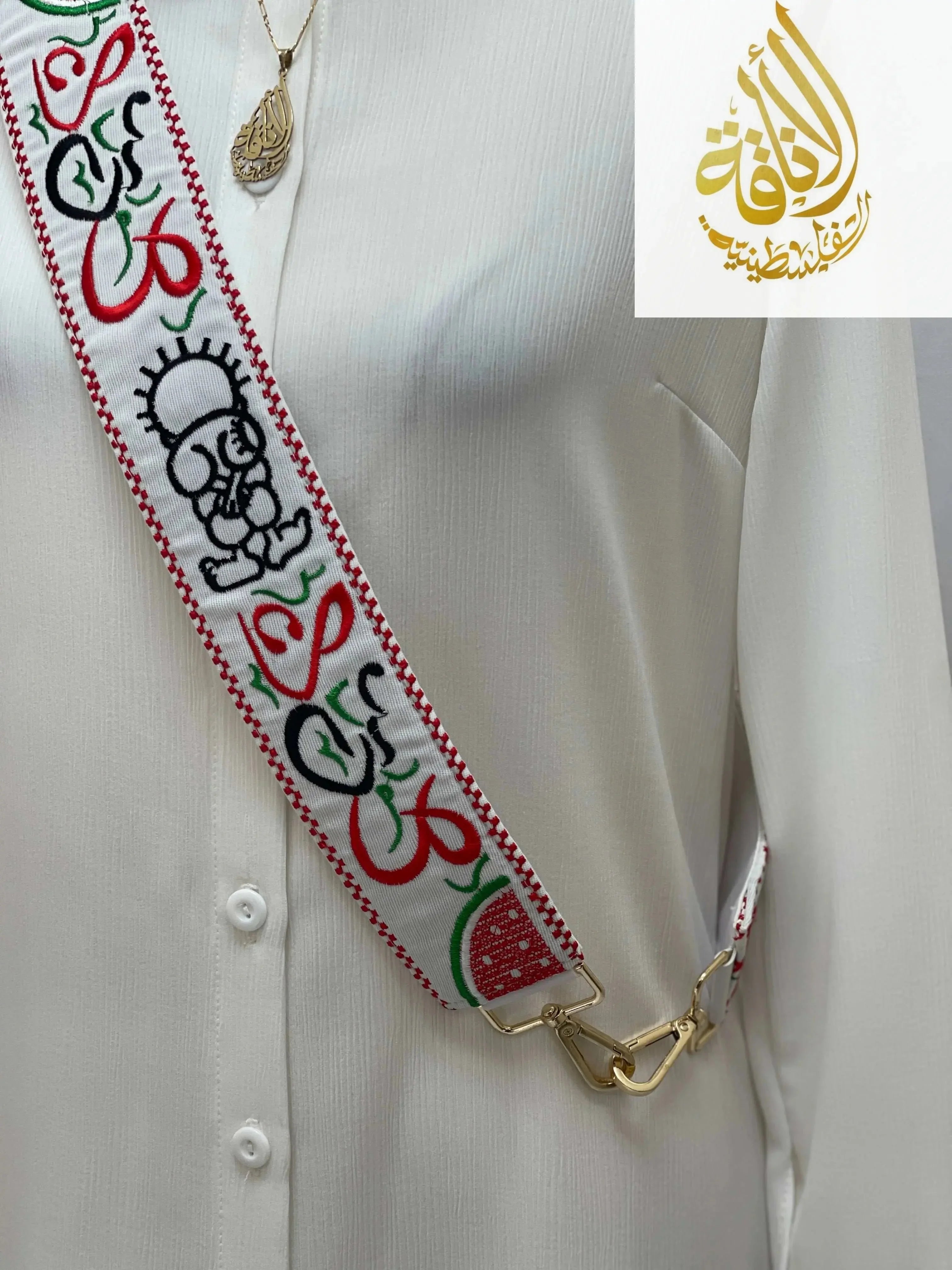 Palestinian embroidered purse strap with colorful traditional patterns on white fabric attached to gold clasps