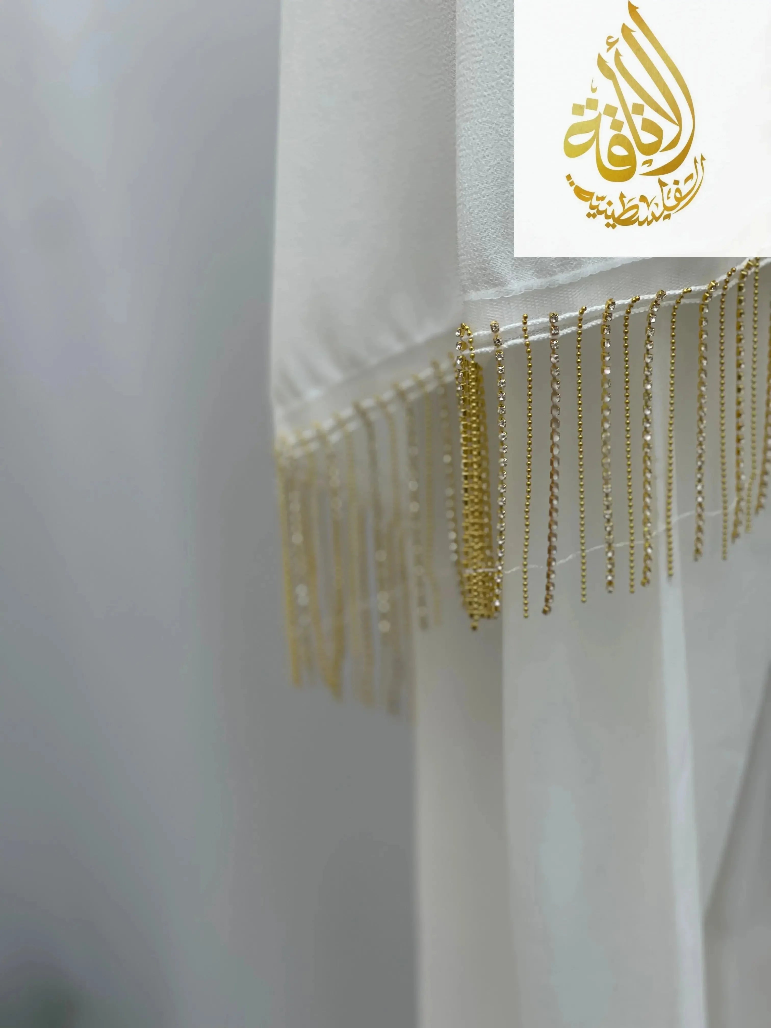 White fabric embroidery with delicate gold thread fringe detail Palestinian Traditional Modest Fashion Kasab Khirka